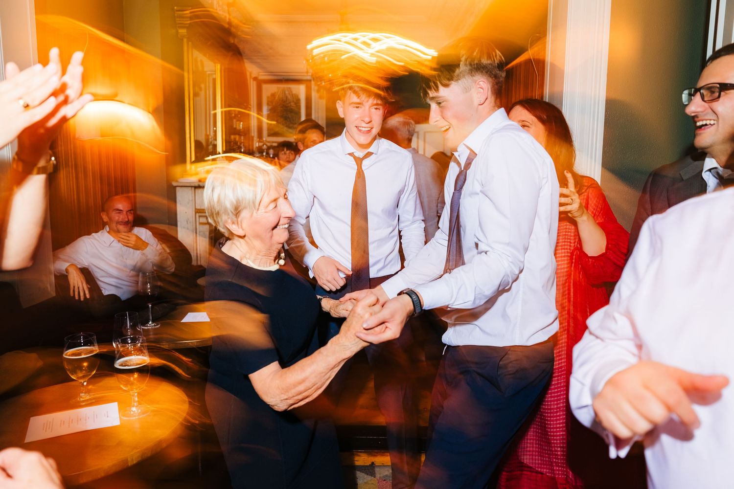Joyful guests dancing and celebrating at an elegant indoor wedding reception party.