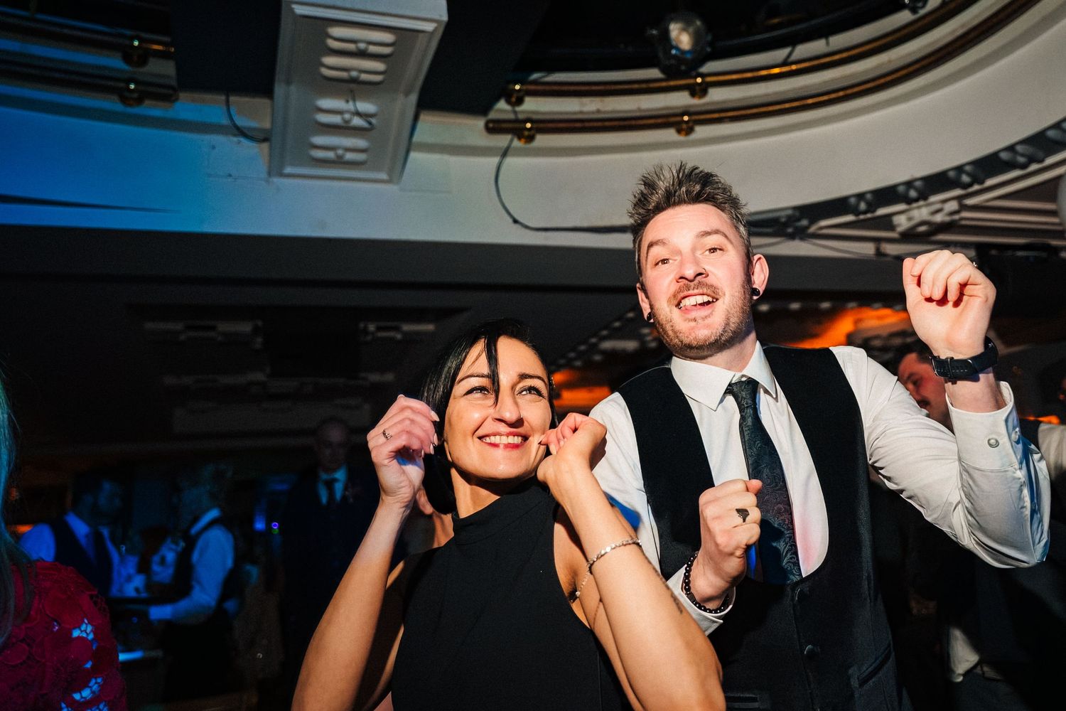 Party guests having fun and dancing under blue lighting at an indoor venue. Wedding ceremony at the Set Theatre Langtons Hotel Kilkenny