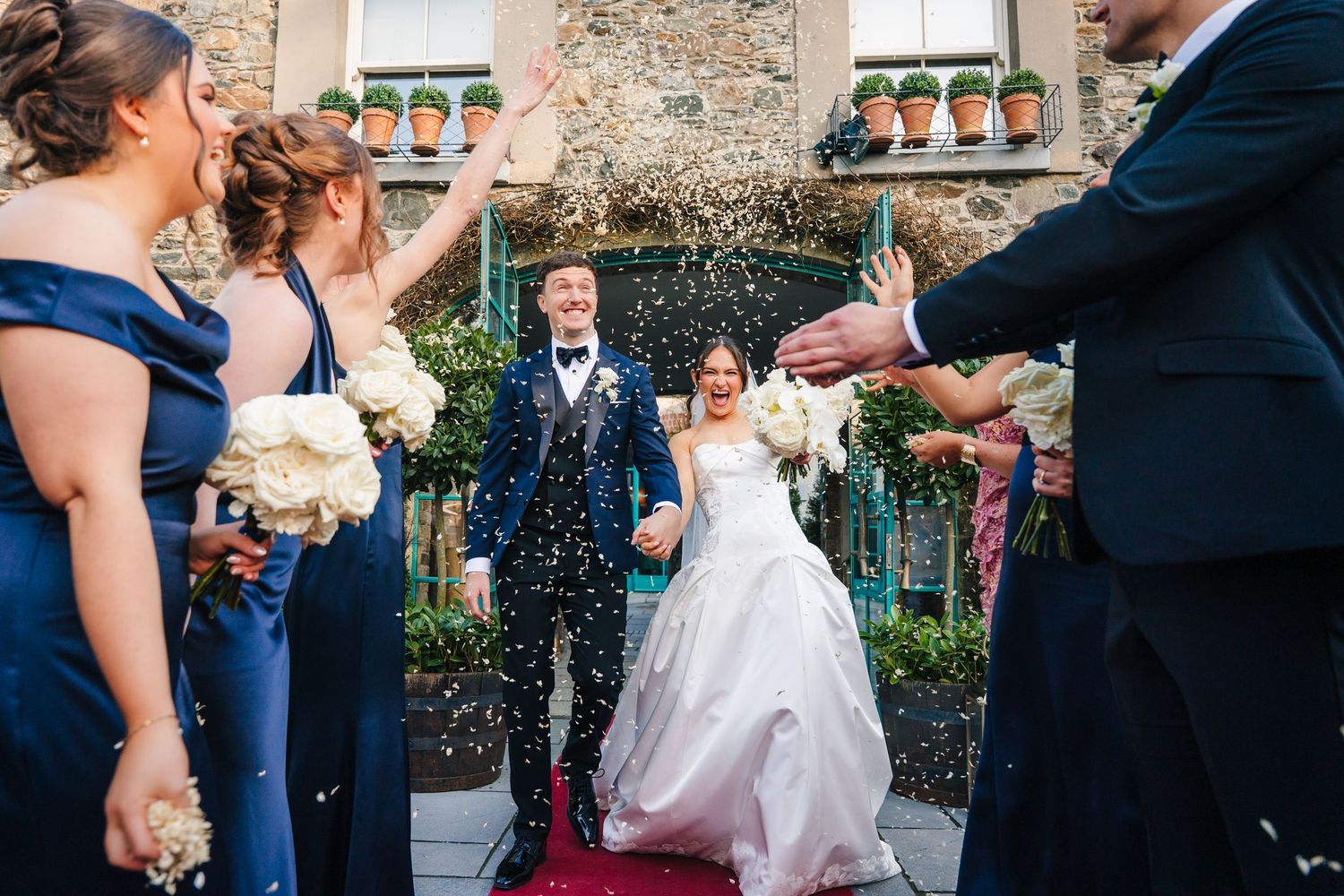 Virginia Park Lodge Wedding photographer Dublin Ireland Meath Cavan Wedding party celebrating with confetti outside historic stone building.