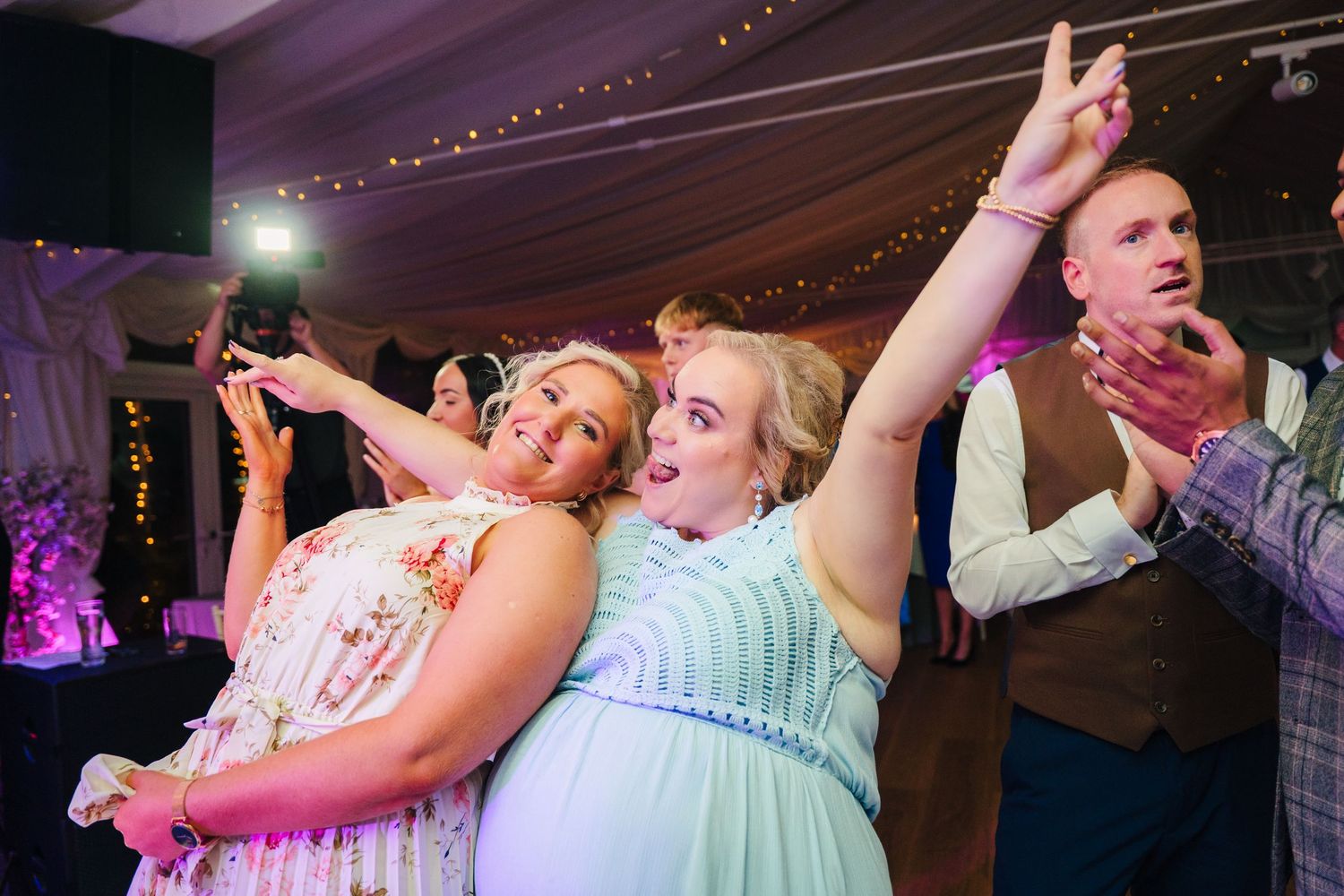 Wedding guests dancing and celebrating on a crowded dance floor with colorful lighting. LGBTQ Ashley Park Wedding Photographer