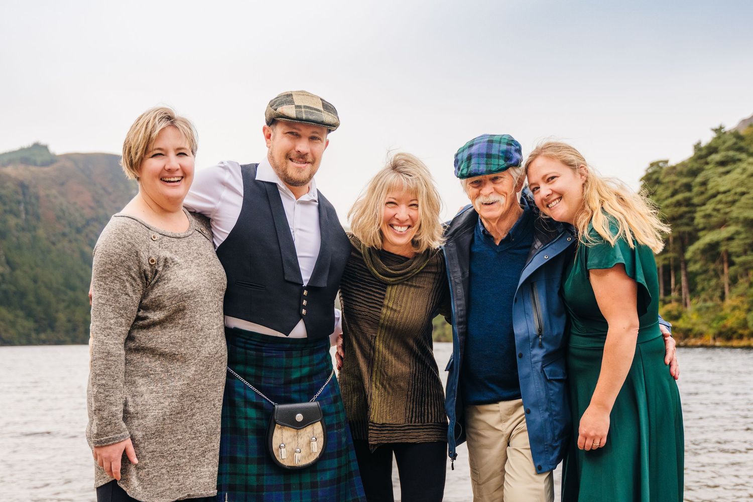 A group of people stand together outdoors in coordinated outfits for a family photo session near a lake.Family photogrAPHER DUBLIN