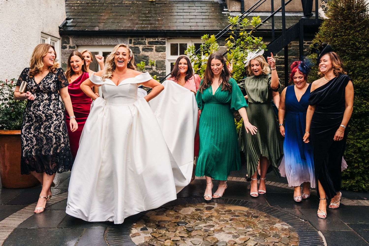 Wedding celebration with guests dancing outdoors in a garden setting with colorful dresses.  Virginia Park Lodge Wedding Photographer Cavan