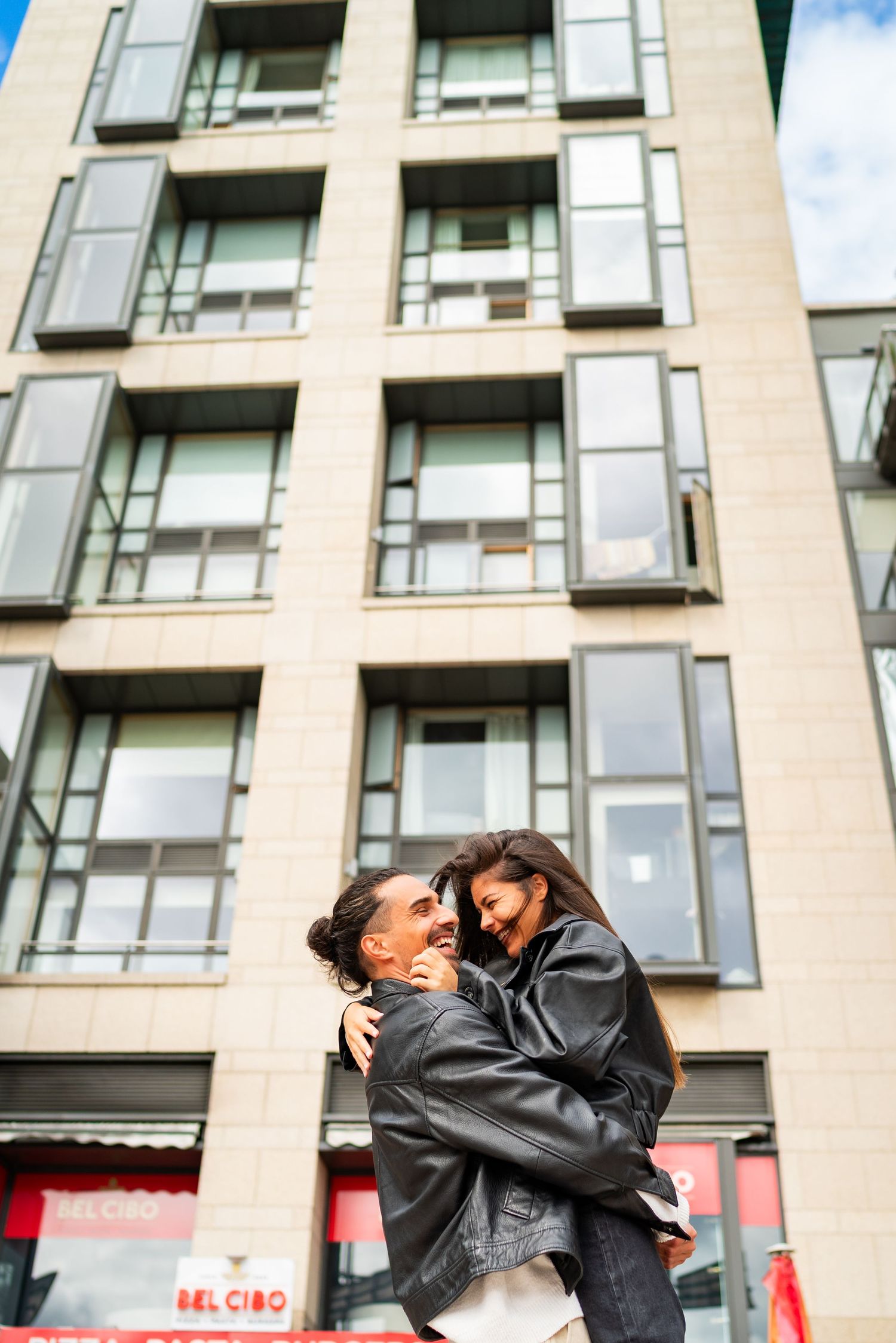 Two people share affectionate moments against a modern apartment building backdrop. Couple's Photoshoot PHOTOGRAPHER Dublin
