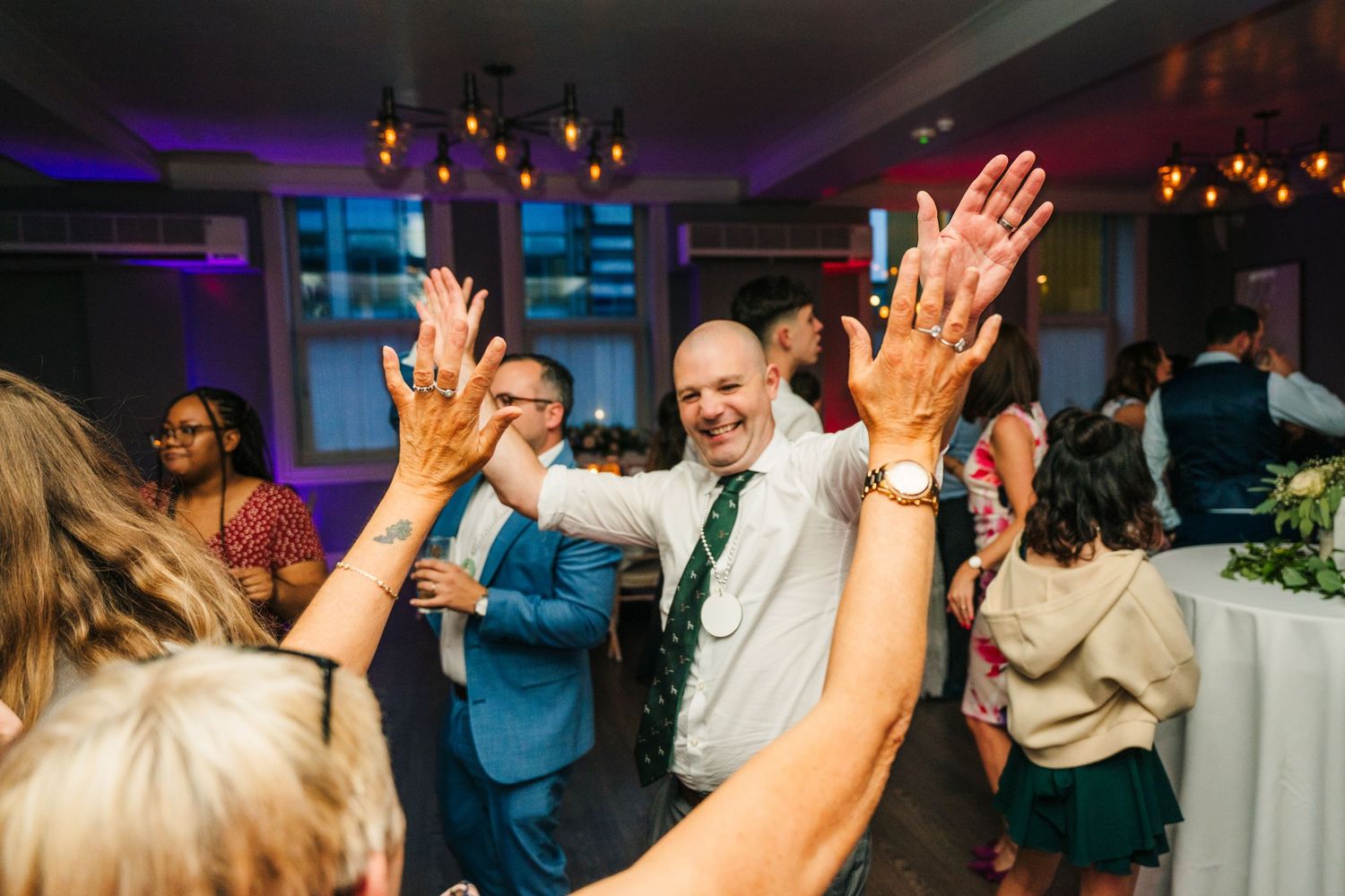 Wedding guests dancing with raised hands during a lively reception party. PHOTOGRAPHER Dublin Ireland Wedding