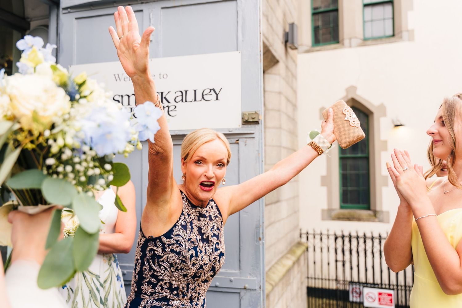 Excited women celebrating joyfully outside a venue with floral arrangements. PHOTOGRAPHER Dublin Ireland Wedding