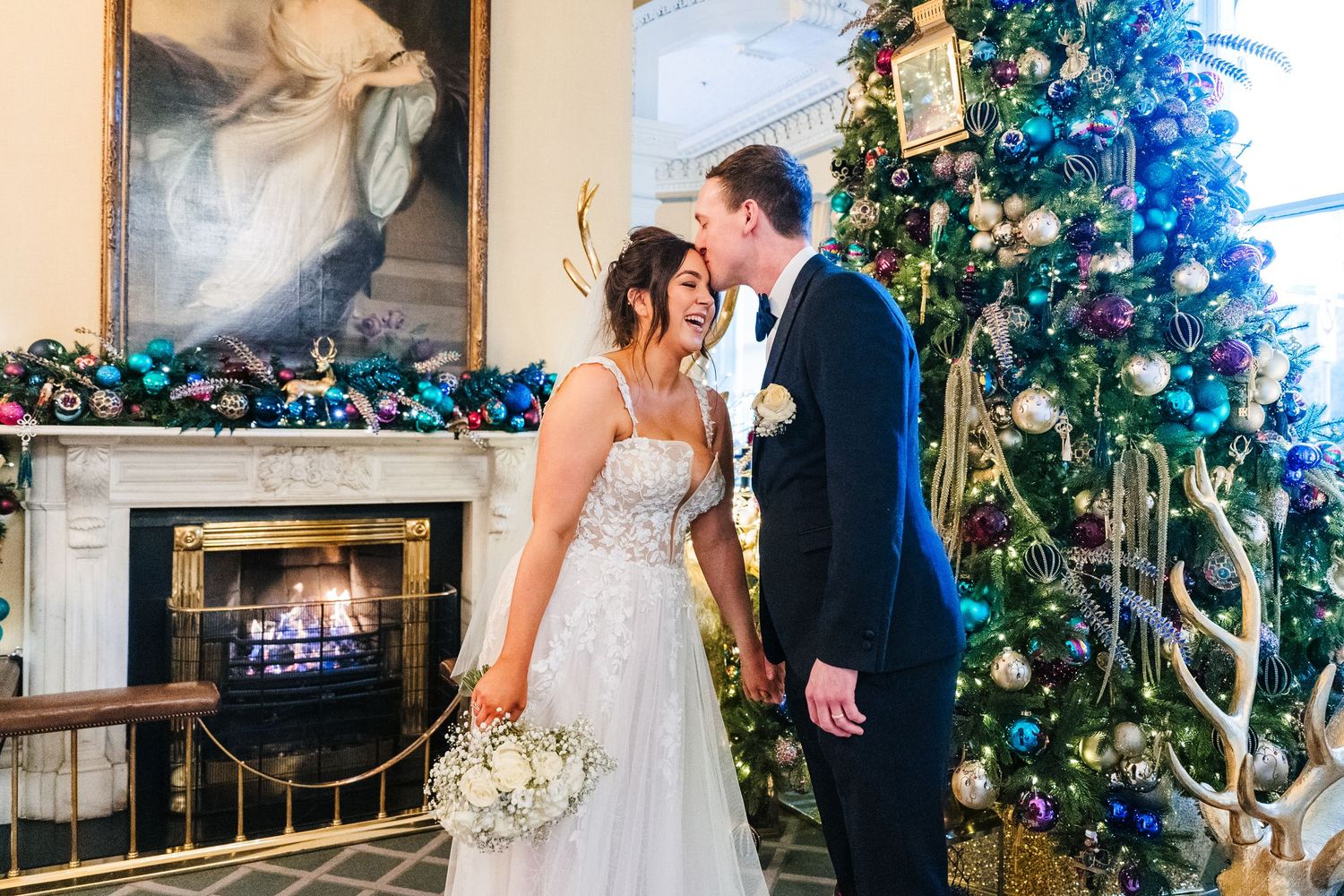 Wedding couple posing by an elegantly decorated Christmas tree in a formal indoor setting. Wedding PHOTOGRAPHER Dublin
