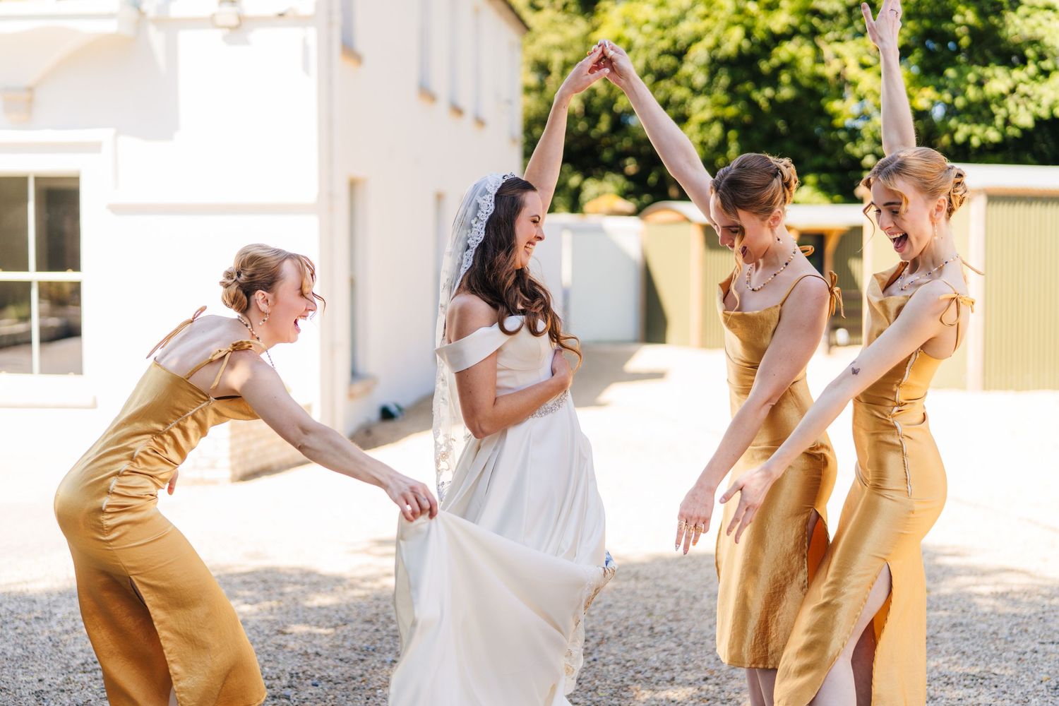 A bride and wedding party have fun dancing and laughing together outdoors in matching yellow outfits.