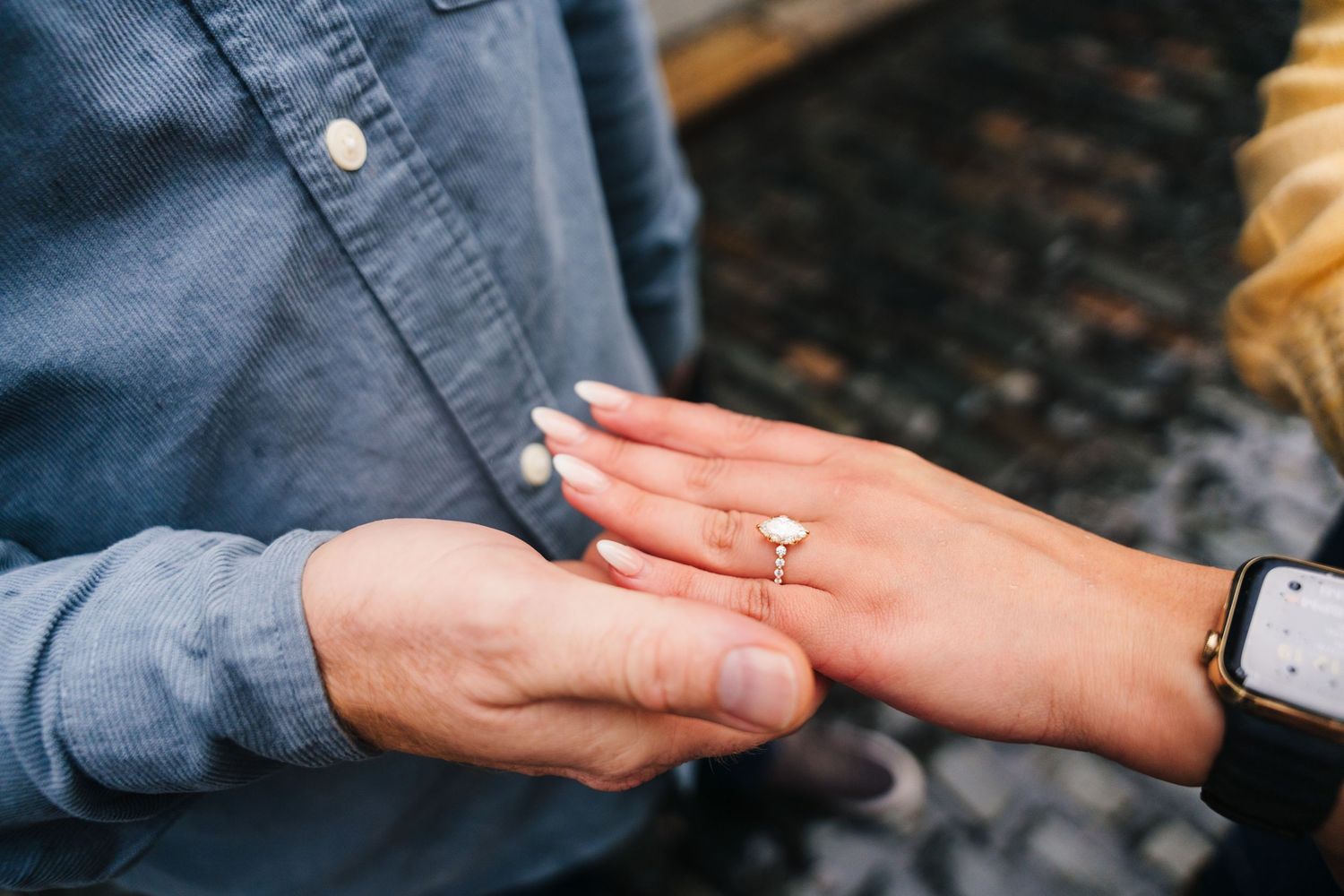 Proposal Dublin Photographer Close-up view of hands showing off a diamond engagement ring with a denim shirt and watch visible.