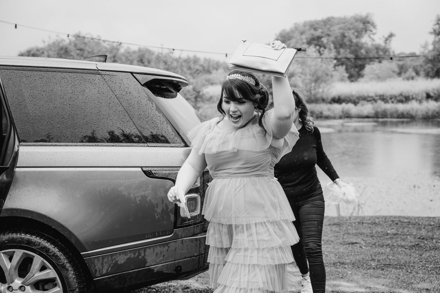 Black and white photo of wedding party members walking together outdoors near parked cars. Wedding photographer Dublin