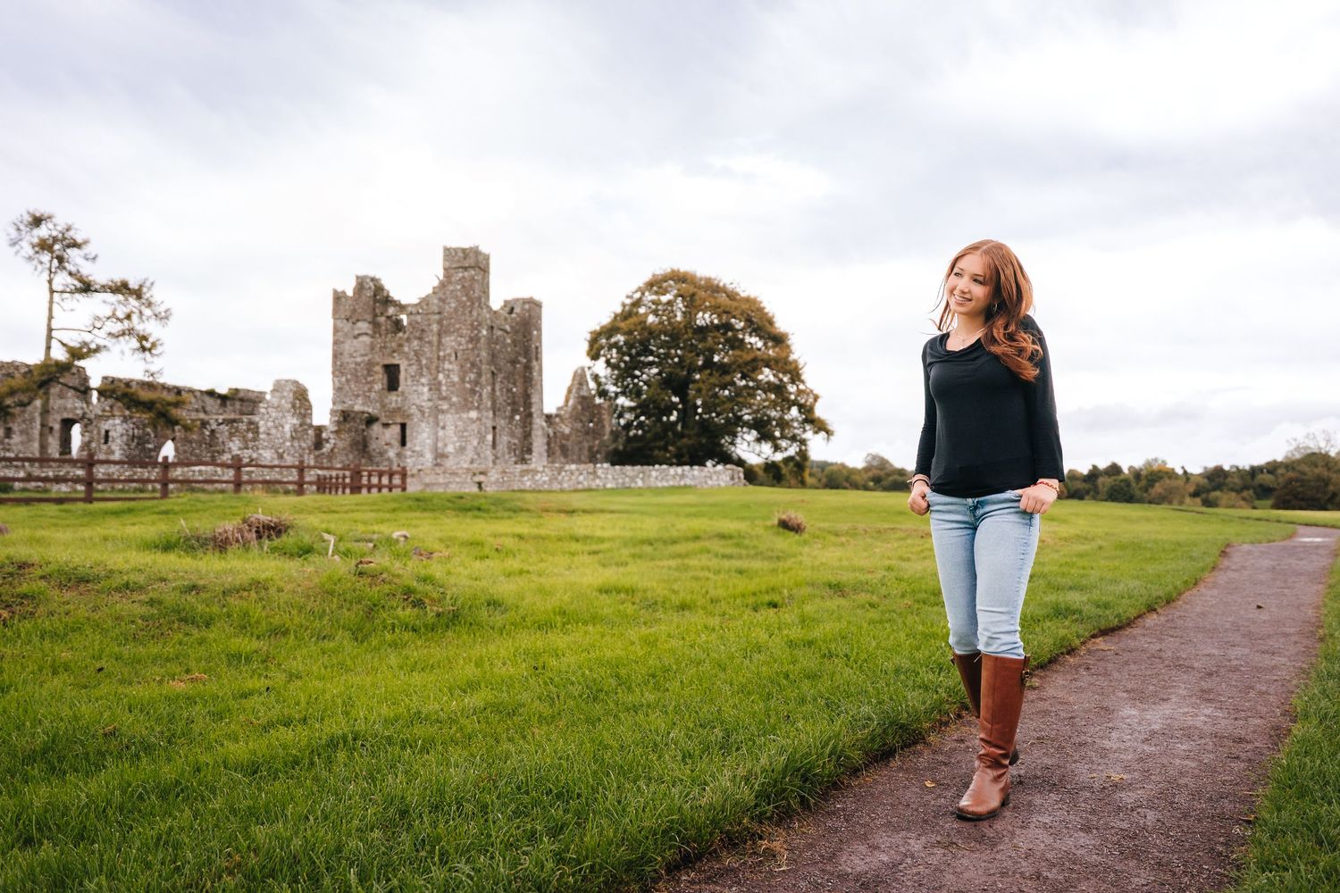Medieval castle ruins stand against a cloudy sky with a winding dirt path leading to the entrance. BEctive abbey family photographer dublin