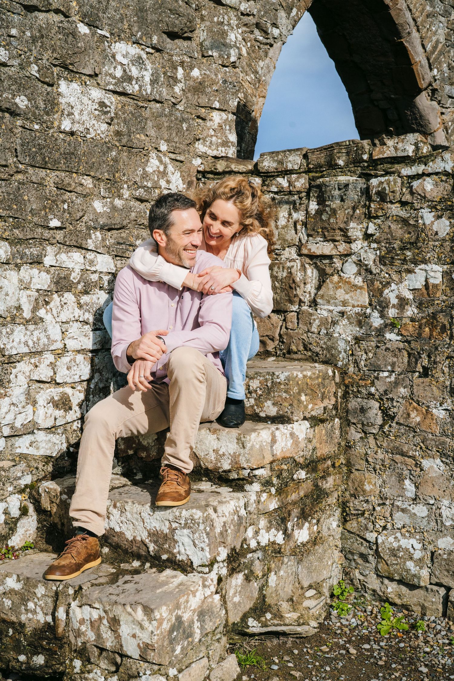 Couple relaxing on ancient stone wall ruins during outdoor photoshoot. BEctive abbey family photographer dublin