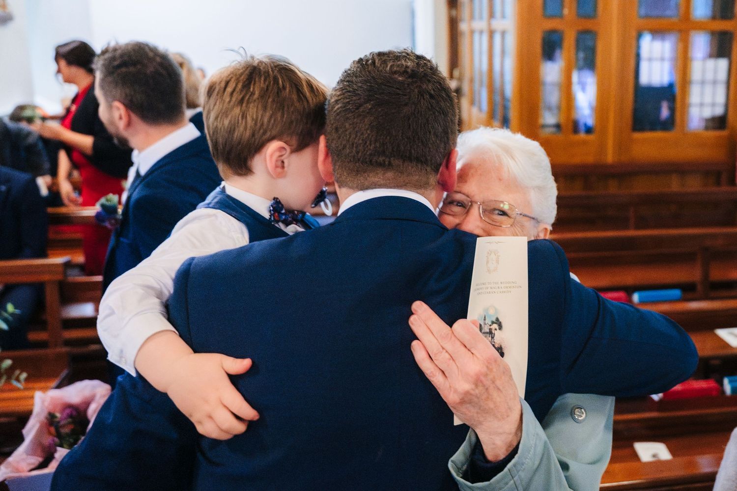 Wedding guests seated in church pews during an emotional ceremony moment.
