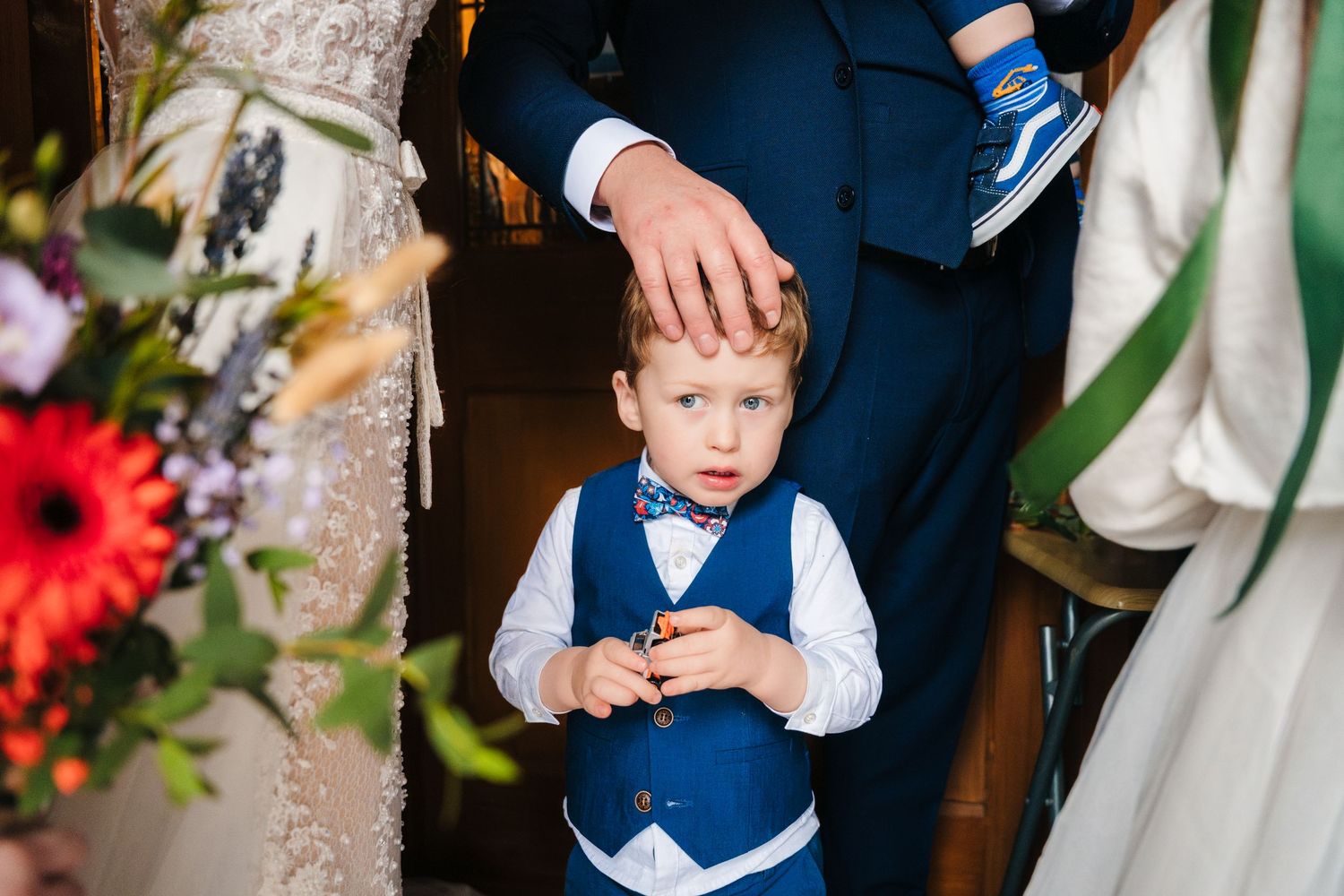Wedding details showing rings, flowers, and formal attire in navy blue and white.