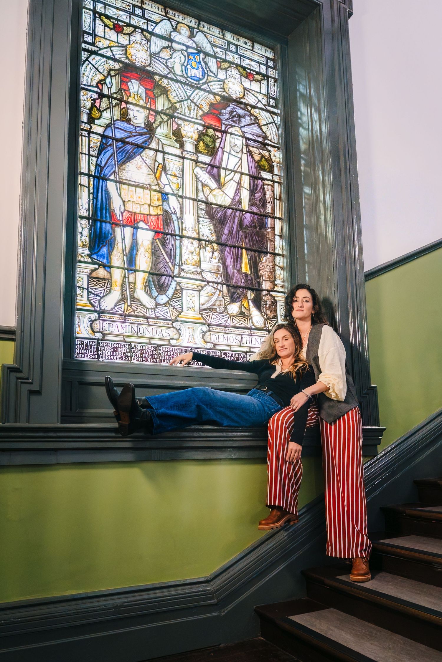 Woman in red striped dress poses near stained glass window in vintage building interior. professional headshots dublin photographer