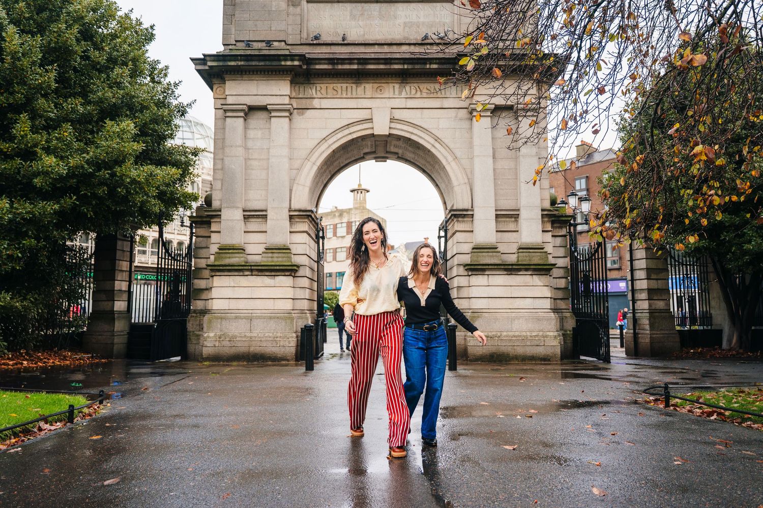 Stone archway frames a path with autumn trees and historic architecture. professional headshots dublin photographer