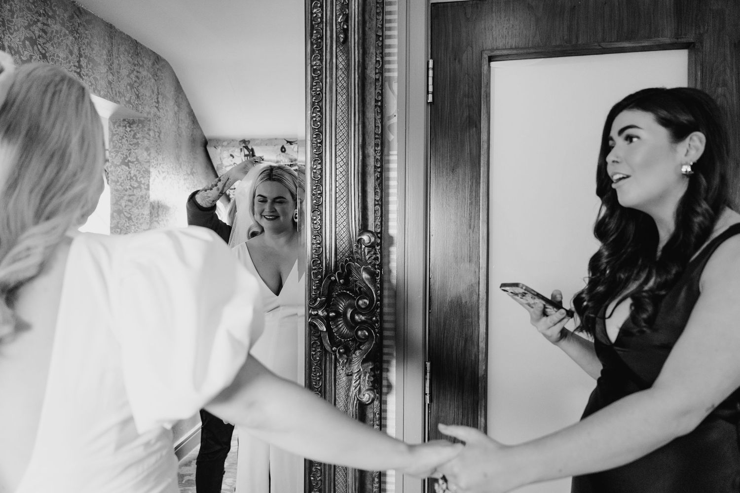 Two people getting ready in a room with a mirror on the wedding day. Wedding photographer dublin