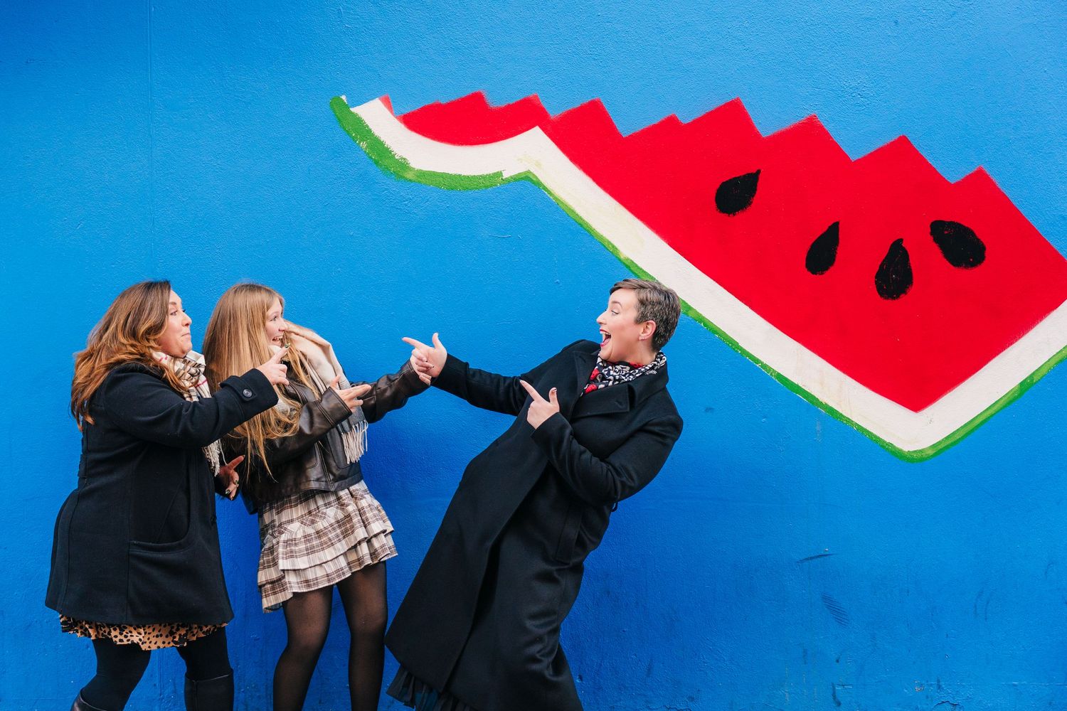 Creative watermelon-themed photo series with people posing against bright blue background. family photogrAPher dublin