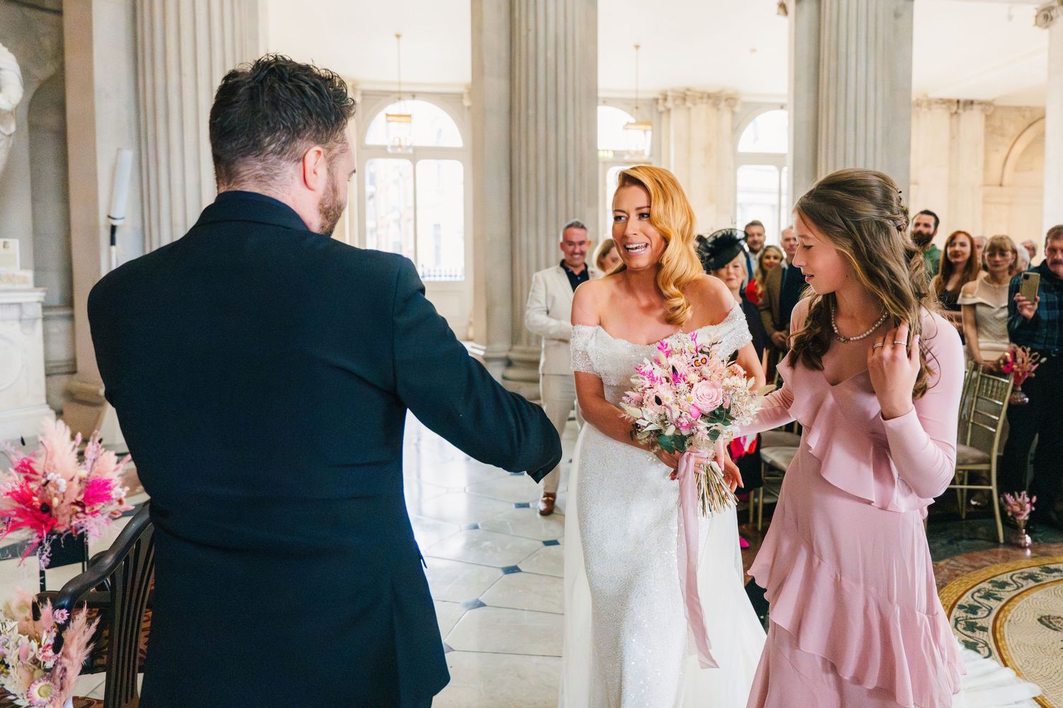 Wedding ceremony moment captured in an elegant indoor venue with columns and natural light.  city hall dublin wedding photos