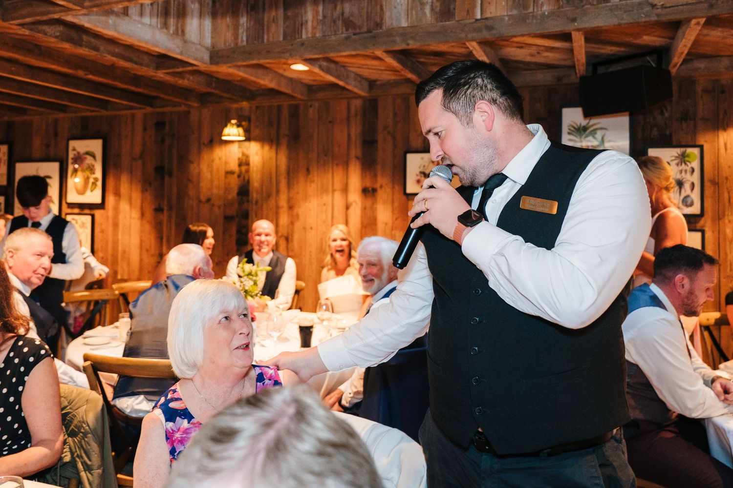 Wedding guests dance and socialize at a rustic reception venue with wooden beam ceiling. The Dean Dublin Wedding Photographer