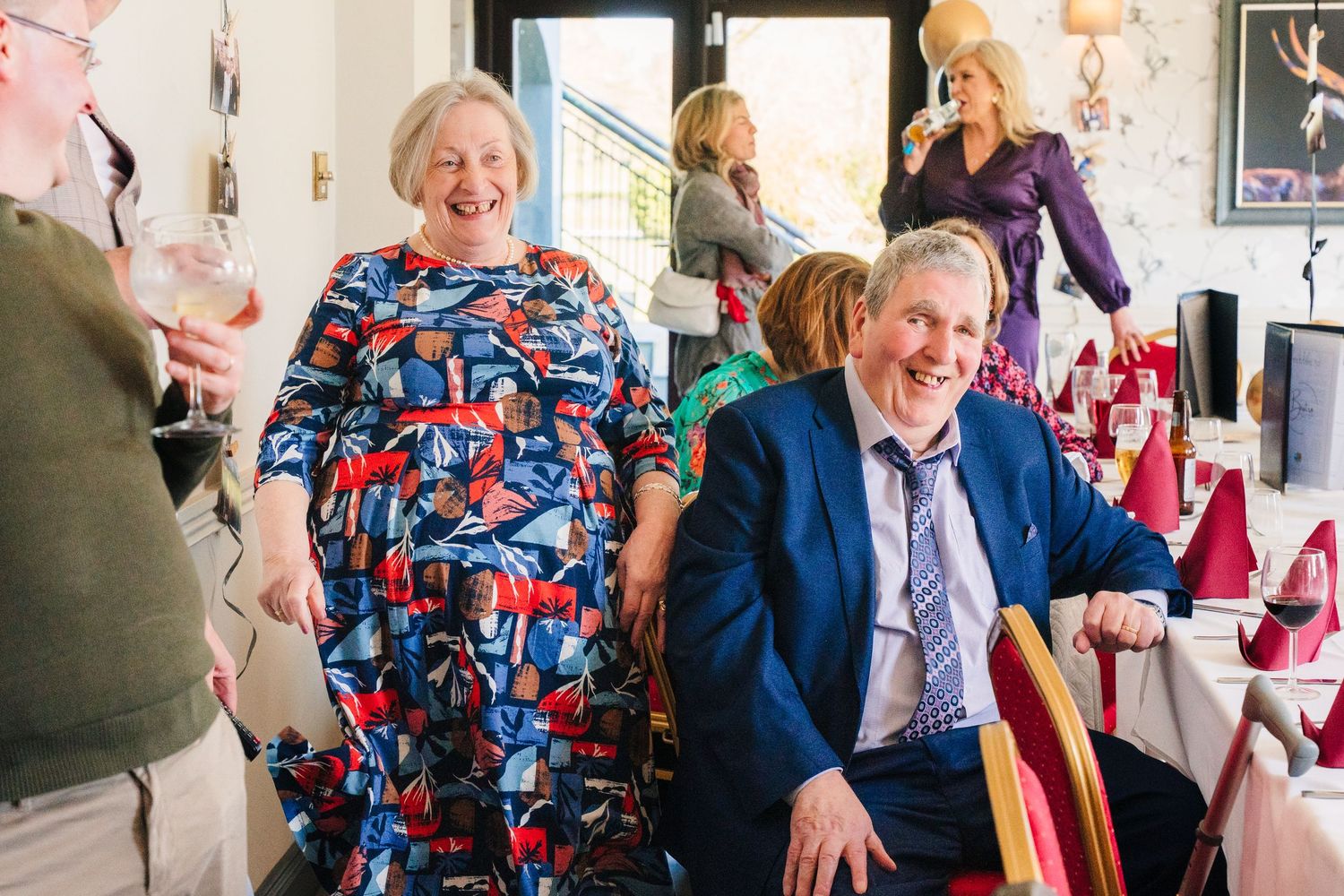 A joyful party scene at what appears to be a celebration with people smiling and laughing in a restaurant setting. family PHOTOGRAPHER Dubli