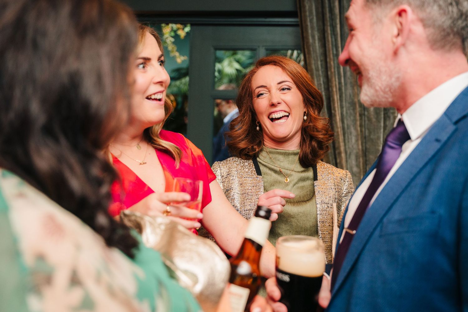 Wedding guests enjoying drinks and conversation at an indoor reception.