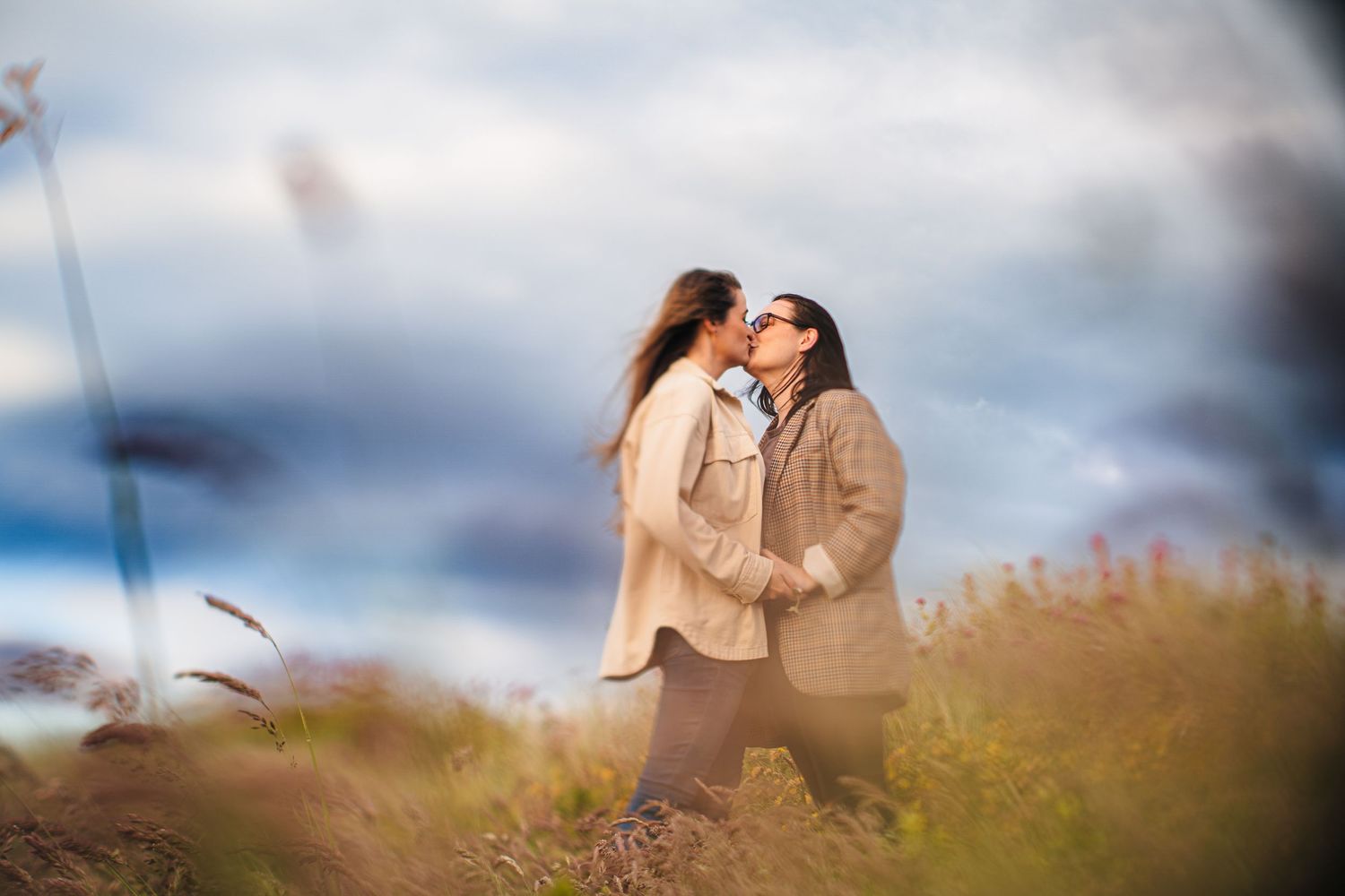 A romantic couple shares an intimate moment in a sun-drenched meadow of tall grass at golden hour. PHOTOGRAPHER Dublin ireland