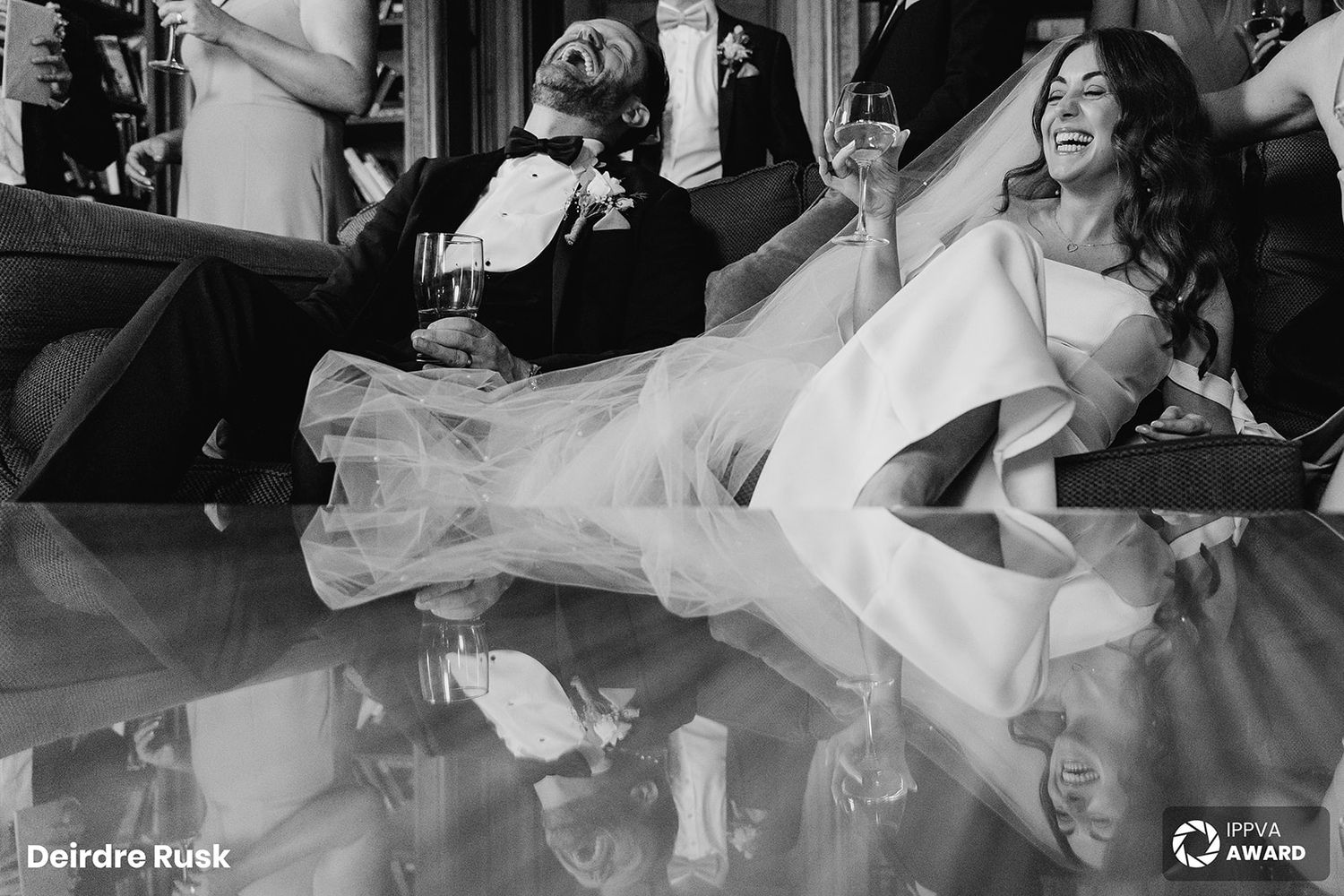 A dramatic black and white photo shows a bride laughing while reclining on a reflective surface. PHOTOGRAPHER Dublin Wedding PHOTOGRAPHER Du