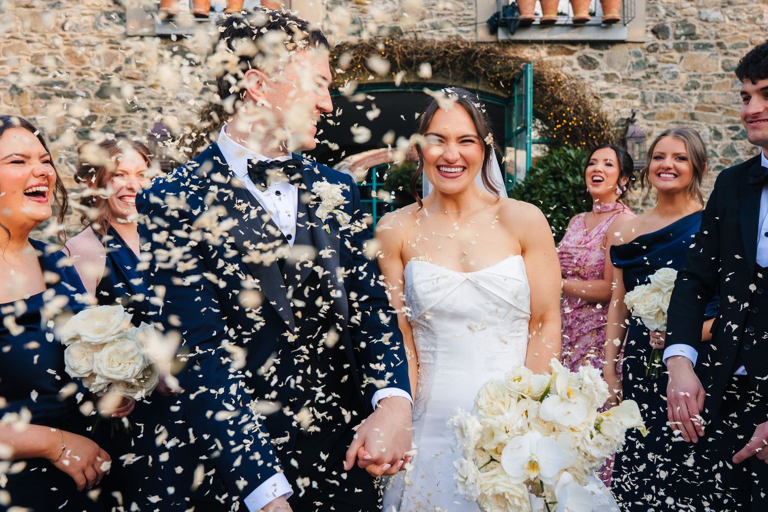 Wedding party celebrating with confetti being thrown outside a stone building. Virginia Park Lodge Wedding photographer Dublin Ireland Meath
