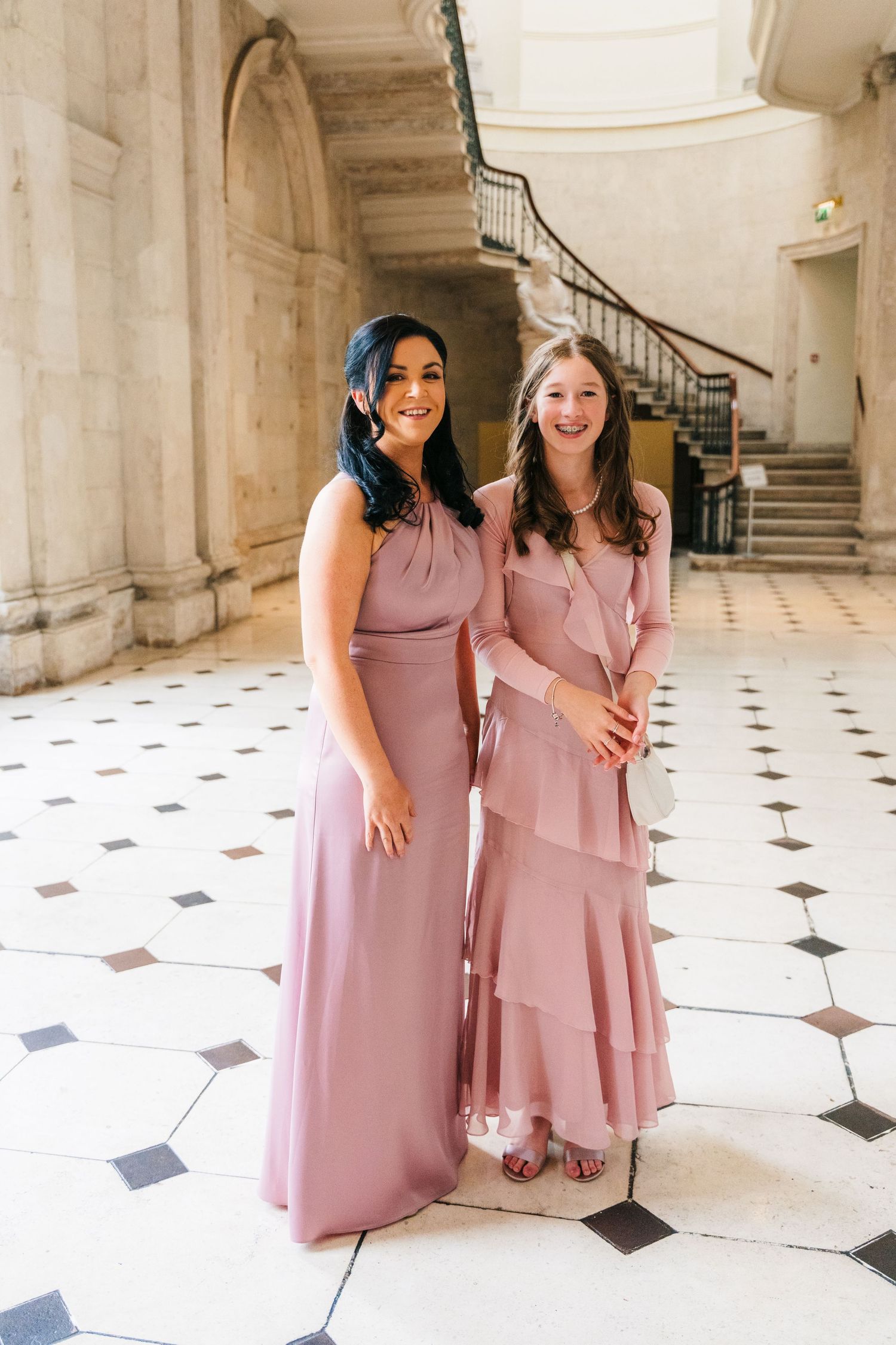 Bridesmaids in dusty pink dresses pose together in an elegant marble hallway with geometric floor tiles.  city hall dublin wedding photos