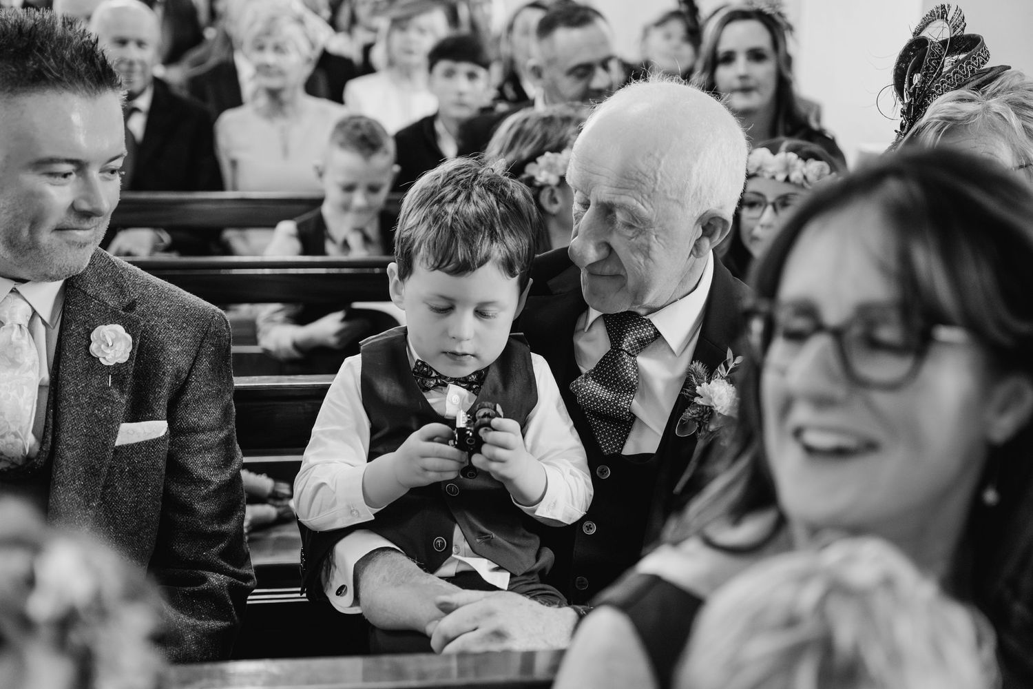 Black and white candid shot of wedding guests reacting during ceremony.