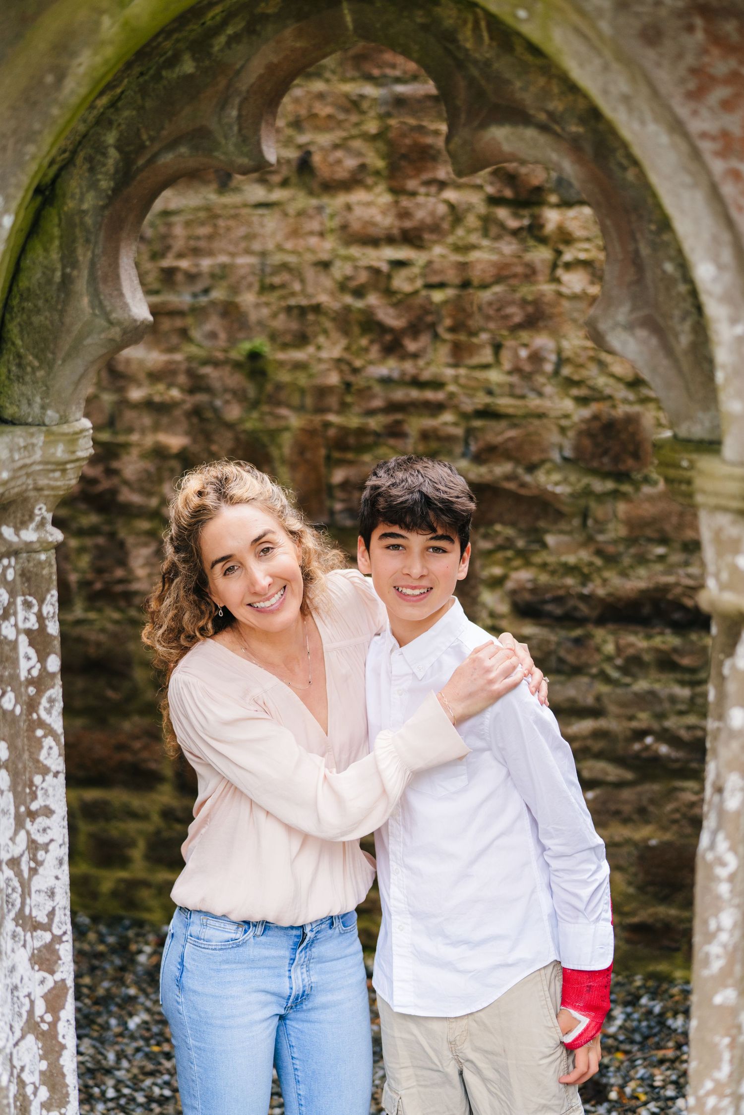 Candid moments captured under stone archways at historic ruins site. BEctive abbey family photographer dublin