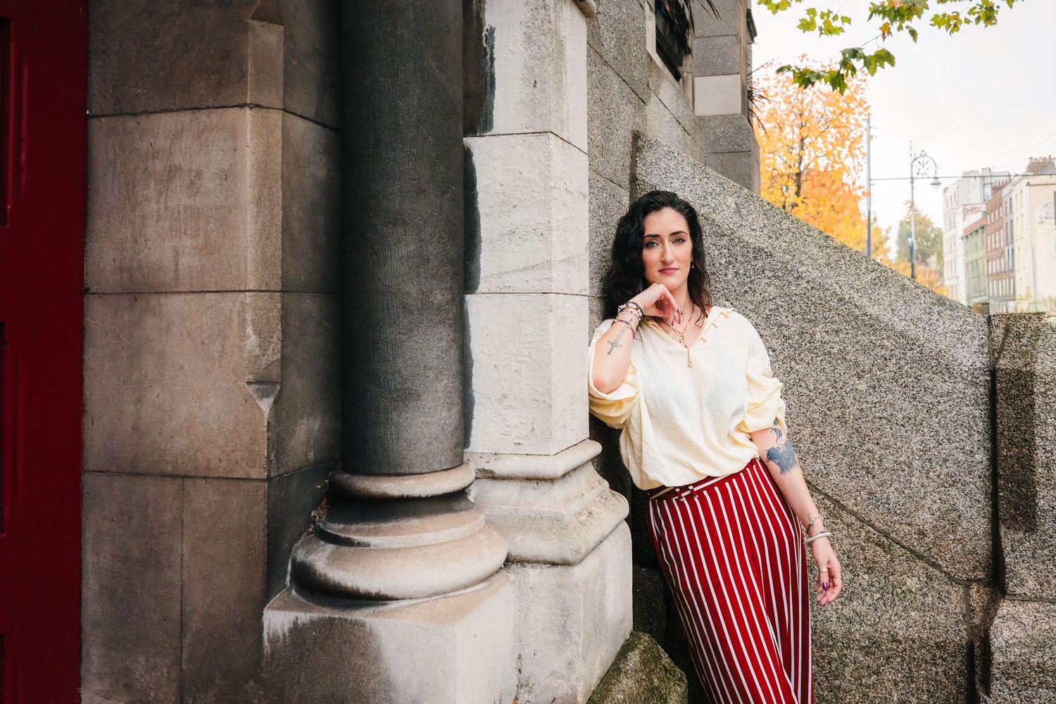 Two people stand between stone columns of a historic building during an autumn photoshoot. professional headshots dublin photographer