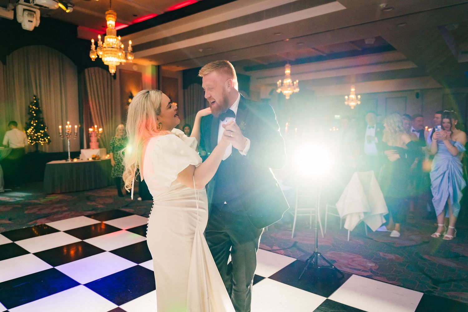 Couple dancing on a black and white checkered floor under crystal chandeliers at an elegant reception venue. City Hall Dublin Photographer