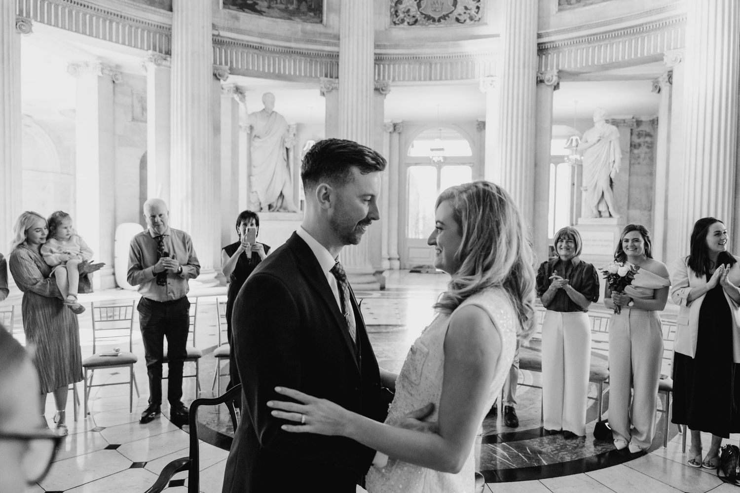 Wedding celebration inside an elegant white-columned hall with classical architecture. City Hall Dublin wedding photogrAPher