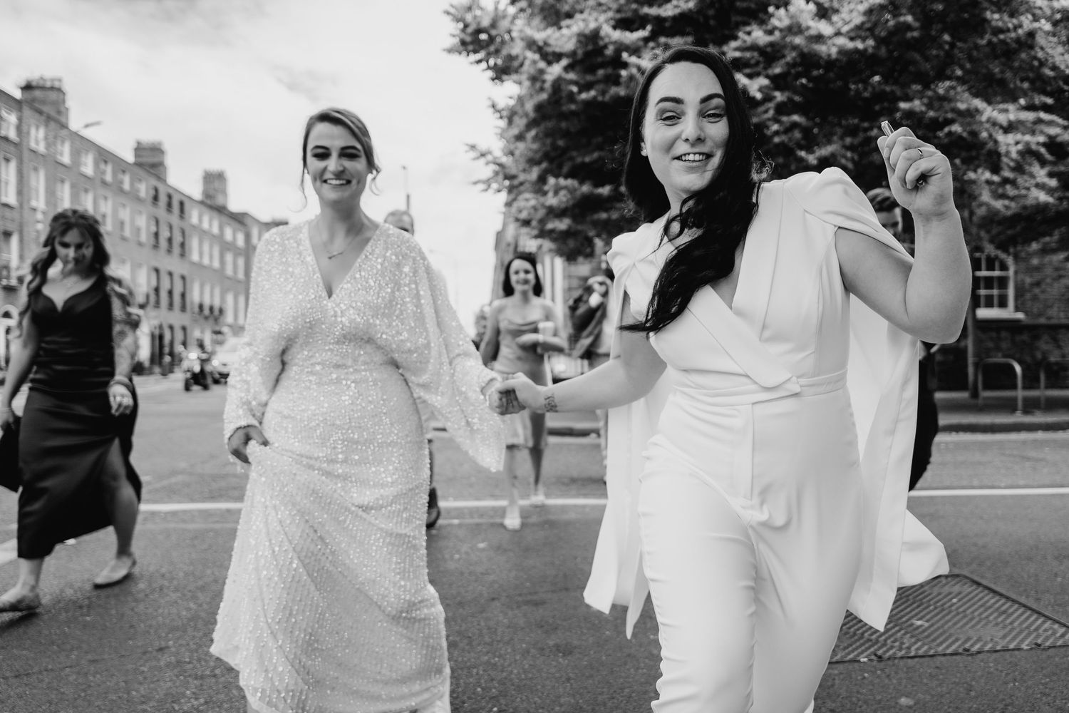Two people in white outfits walk together on a city street in black and white photography. House Dublin Wedding Photographer