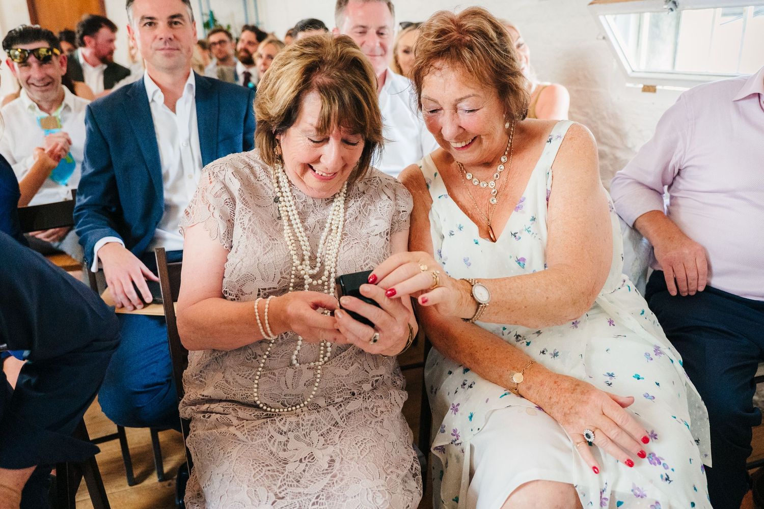 Wedding celebration candid moments showing guests sharing laughter at reception tables. Same sex wedding PHOTOGRAPHER Dublin
