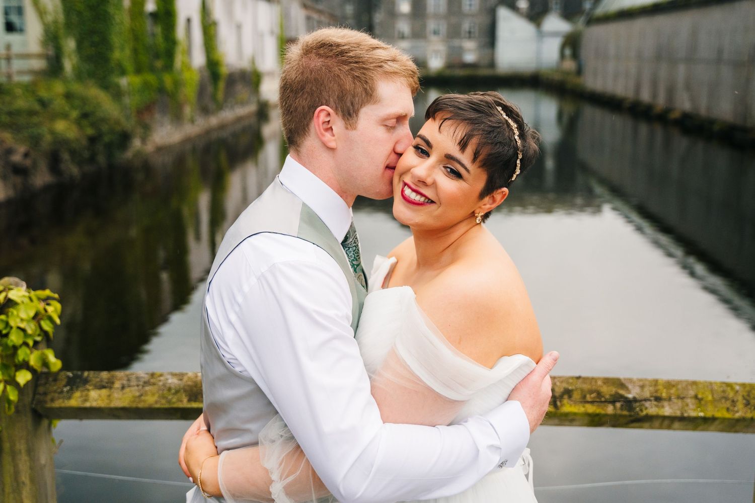 Millhouse slane wedding photographer dublin Intimate wedding portrait of a couple sharing a romantic moment by a waterway.