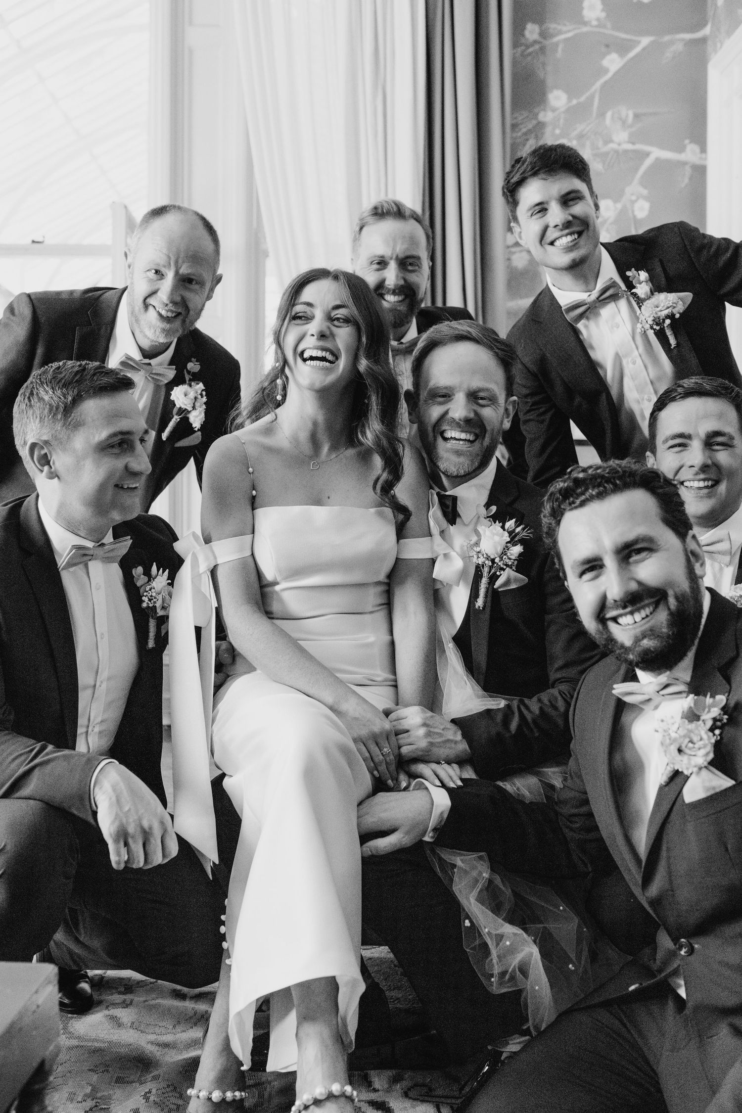 Castle Leslie Wedding Photographer DubliA bridal party shares a candid black and white moment together, laughing joyously in formal attire.