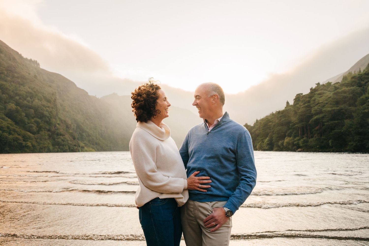 Family photographer Ireland Dublin Couple sharing an intimate moment at sunset by a scenic lake.