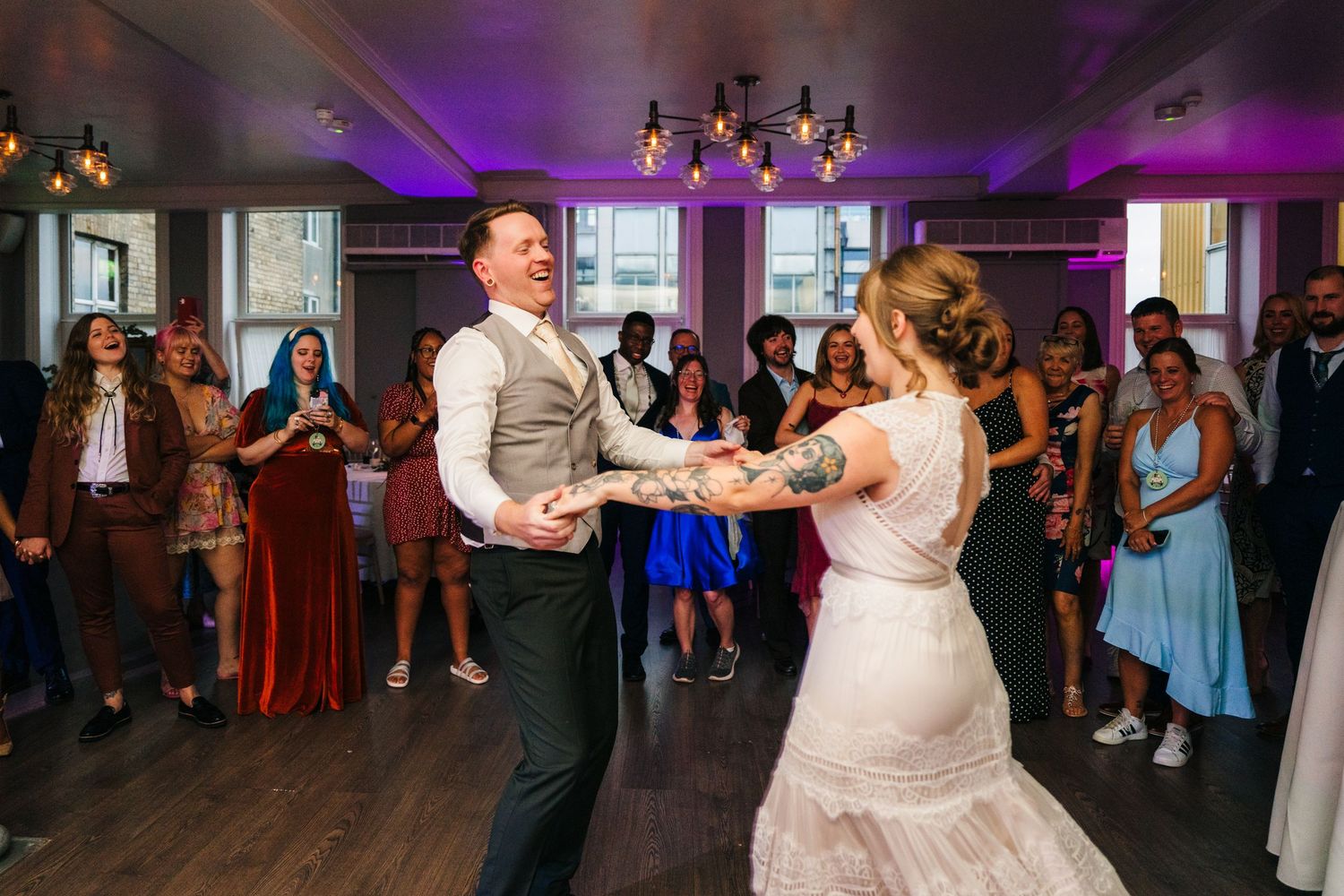 Wedding reception dancing with purple lighting and guests celebrating on the dance floor. PHOTOGRAPHER Dublin Ireland Wedding