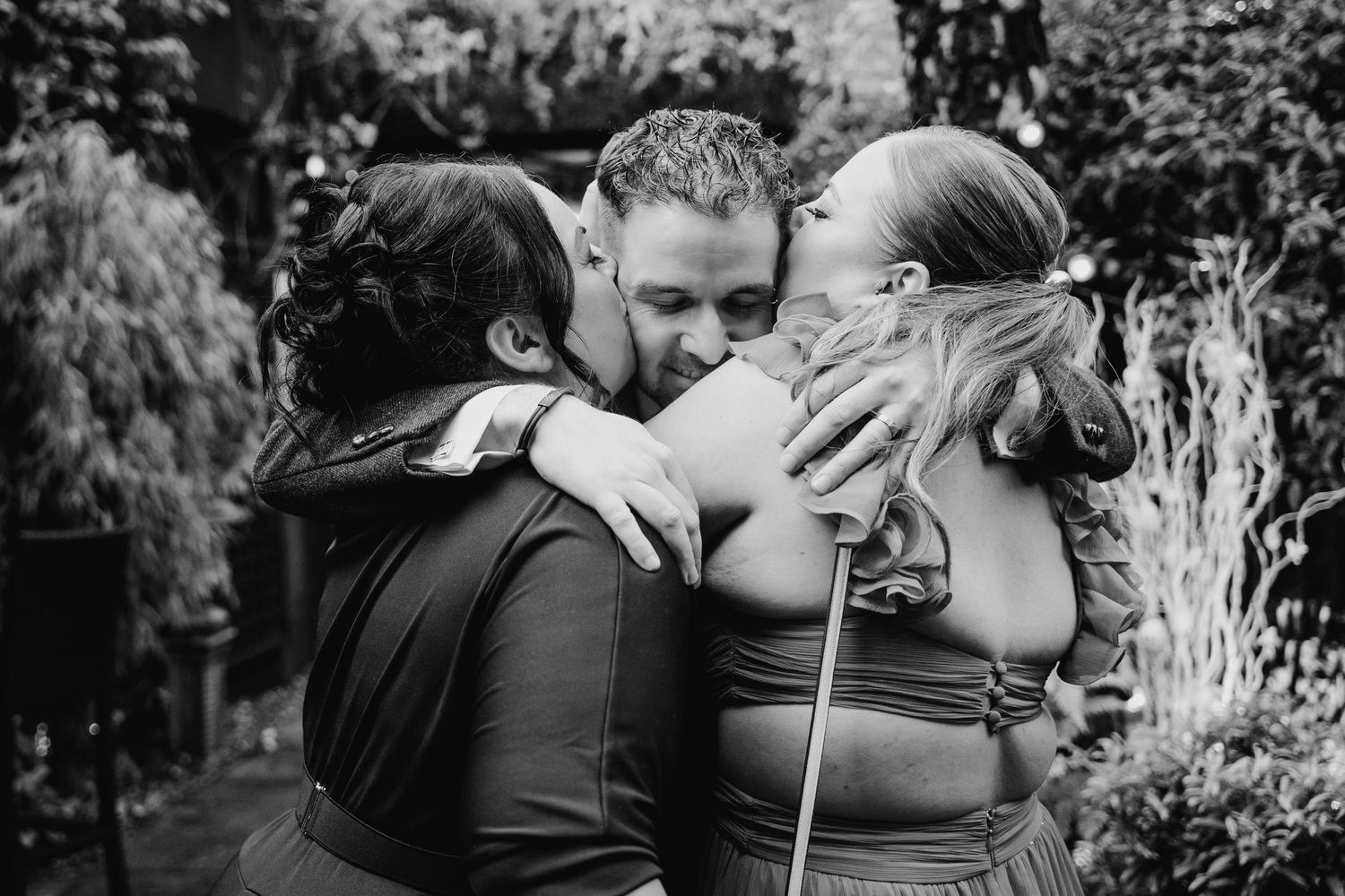 Marco Pierre Dublin Wedding PhotographerA touching black and white moment of three people embracing in an outdoor garden setting.