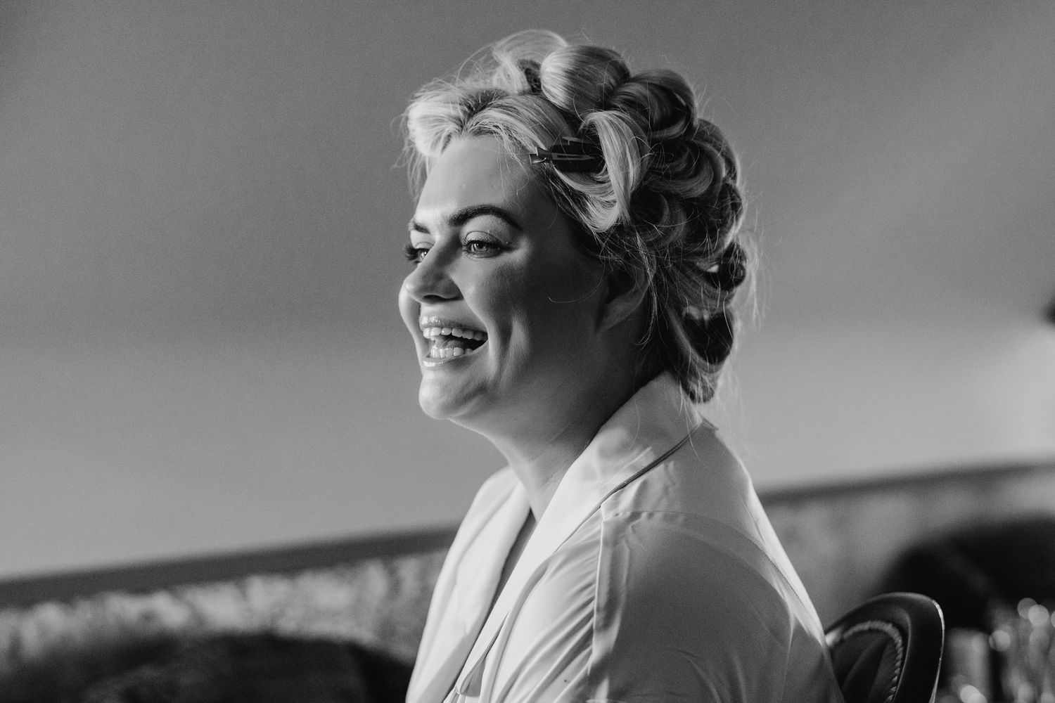 Black and white photo showing joyful wedding preparations with bridesmaids getting ready in a bright room. Wedding photographer dublin