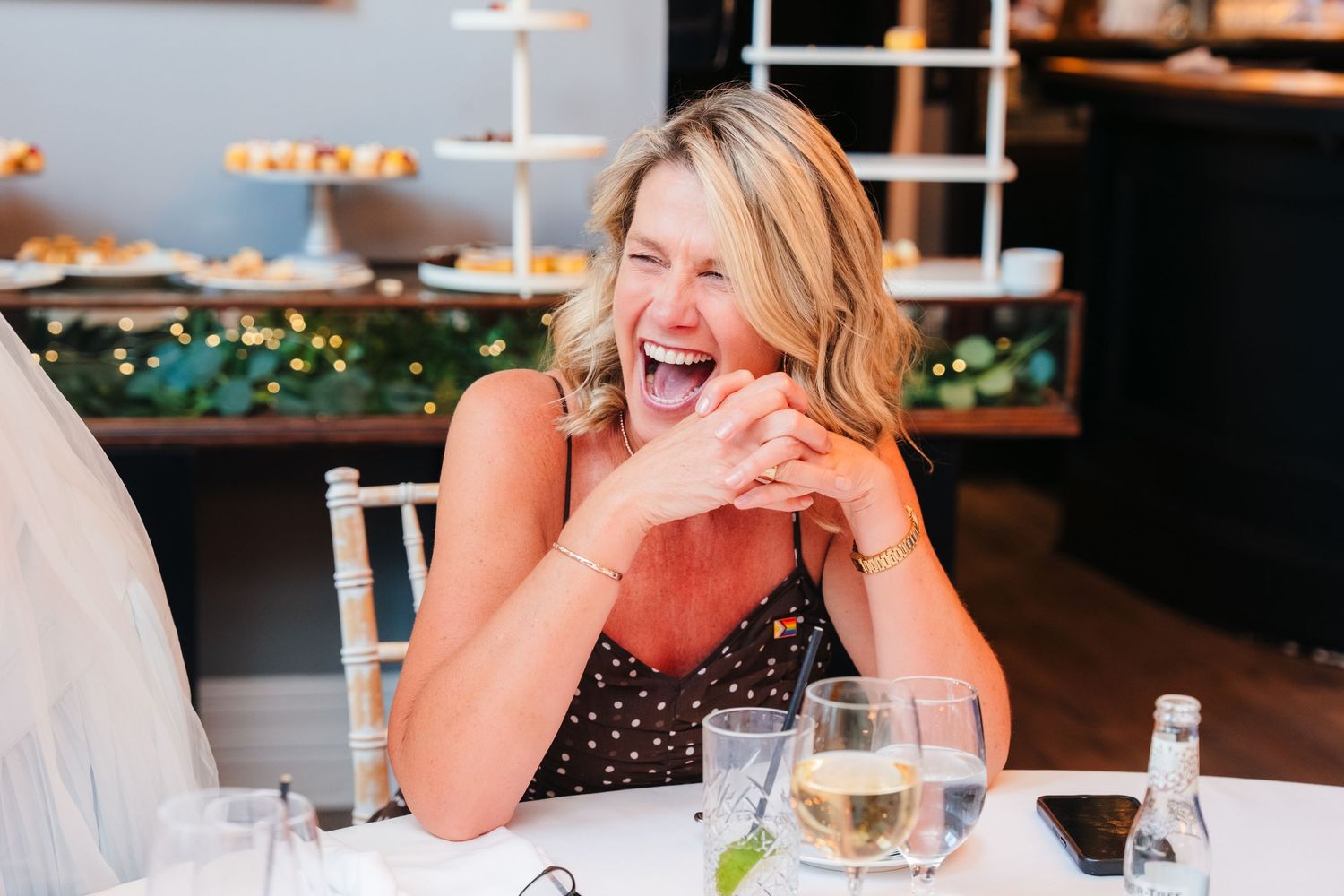 Gay wedding photographer Dublin
LGBTQ+ wedding photographBlonde woman laughs joyfully at a wedding reception table with wine glasses nearby.