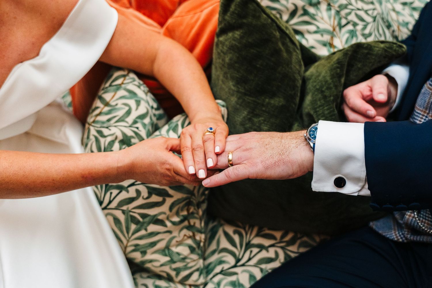 Close-up of hands with wedding rings against a floral patterned background.  Virginia Park Lodge Wedding Photographer Cavan Dublin Ireland