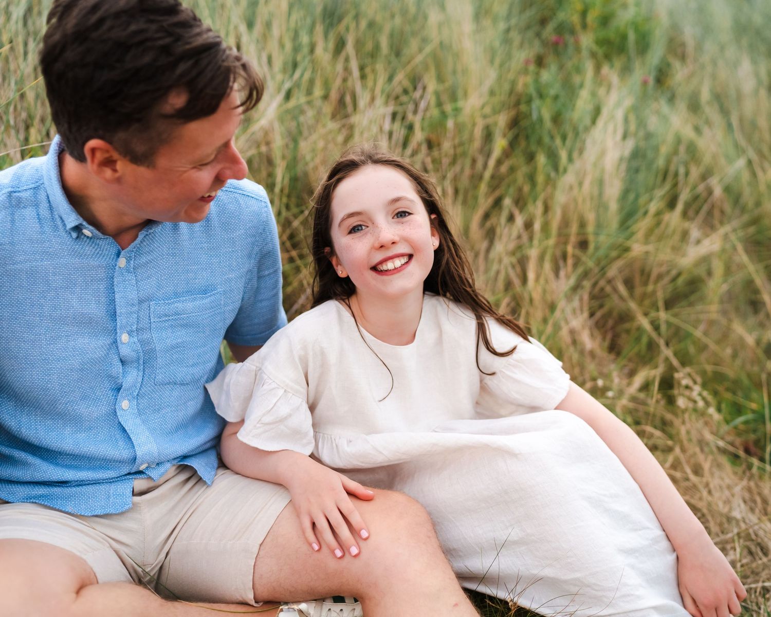 Intimate family photos taken in tall beach grass during golden hour.  Family photographer Dublin Ireland