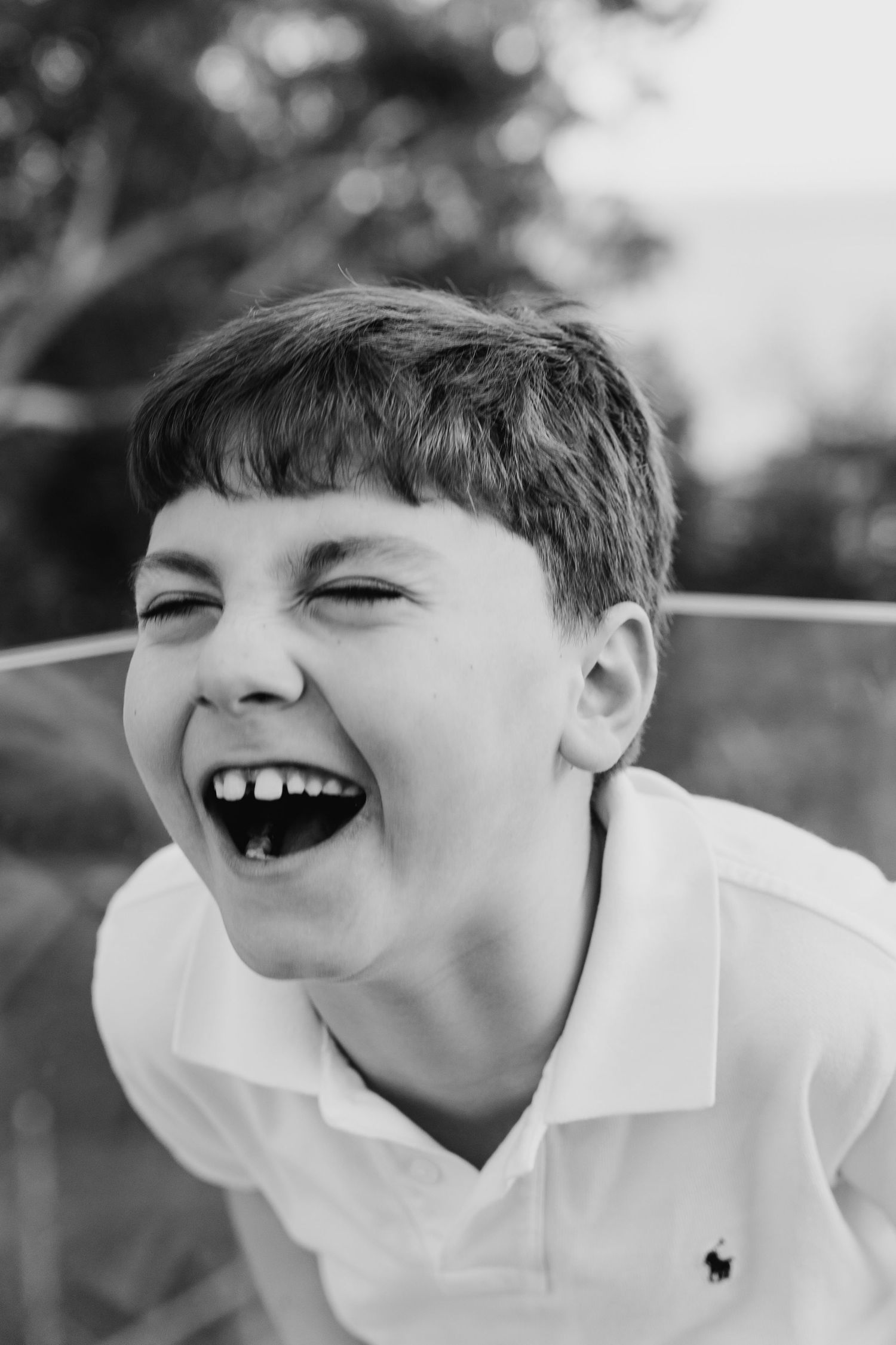 A black and white photo series showing a child in a white polo shirt laughing expressively. family PHOTOGRAPHER Dublin