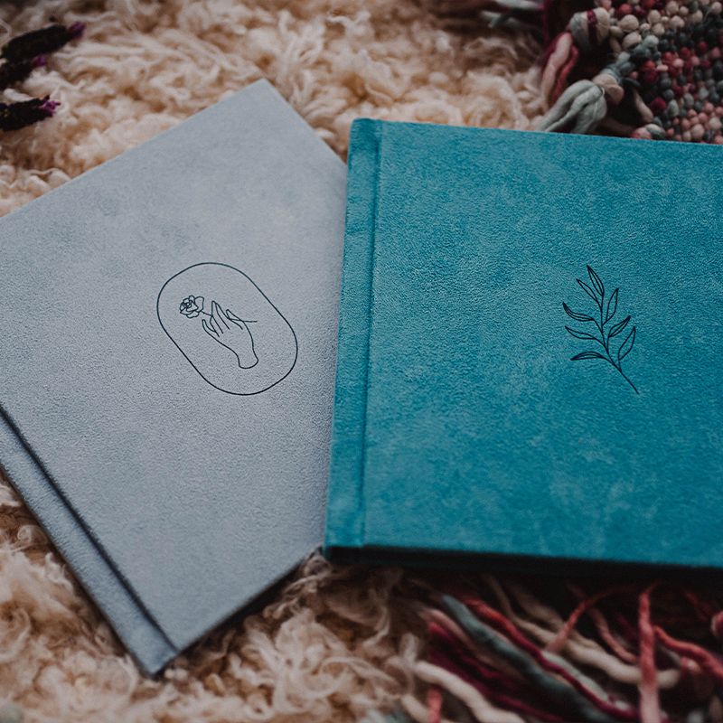Two minimalist notebooks with decorative covers in gray and turquoise colors resting on a textured surface. Wedding photographer Dublin