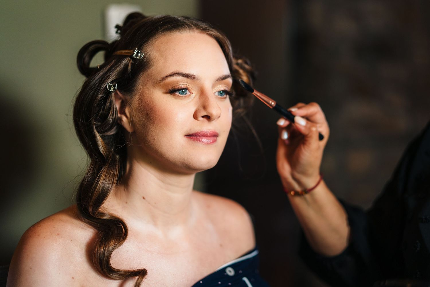 Poulaphouca Wedding photographer wicklow  Professional makeup artist applies finishing touches to bridal makeup.