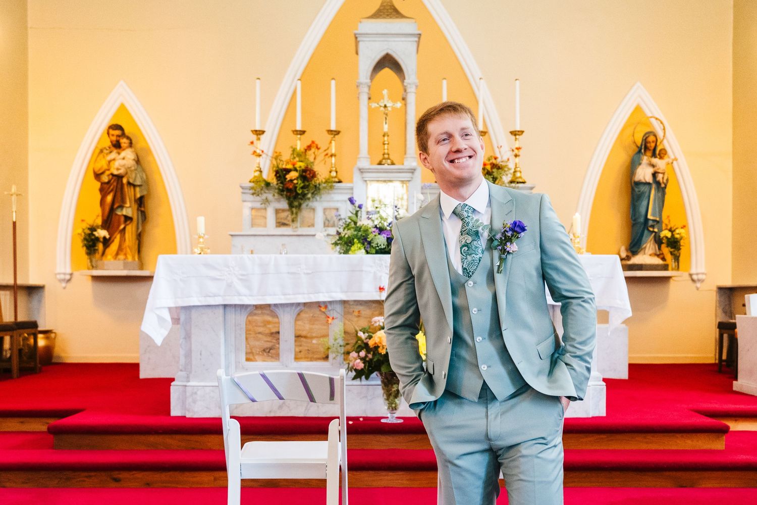 Millhouse slane wedding photographer dublin Groom in light blue suit stands confidently at church altar with religious icons in background.