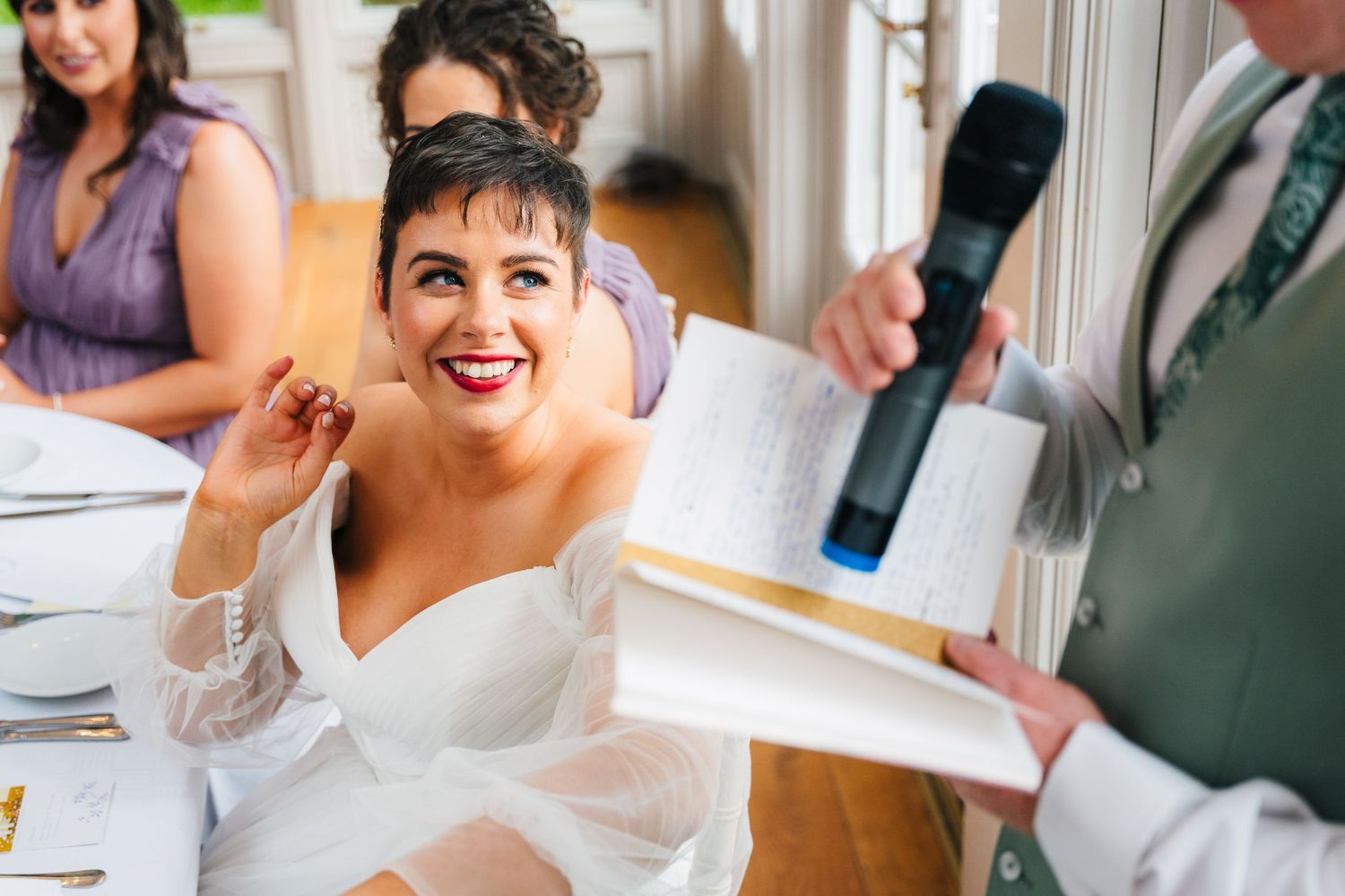 Millhouse slane wedding photographer dublin Joyful bride in white dress reacts during wedding reception speeches.